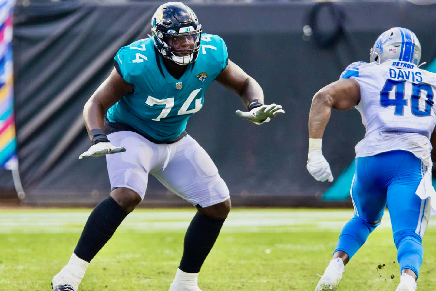 卡姆·羅賓遜與賈拉德·戴維斯 2022 壁紙 — 兩名NFL球員分別穿著青綠色和白色以及藍色和銀色的裝備，在充滿活力的綠色場地上激烈競爭。
