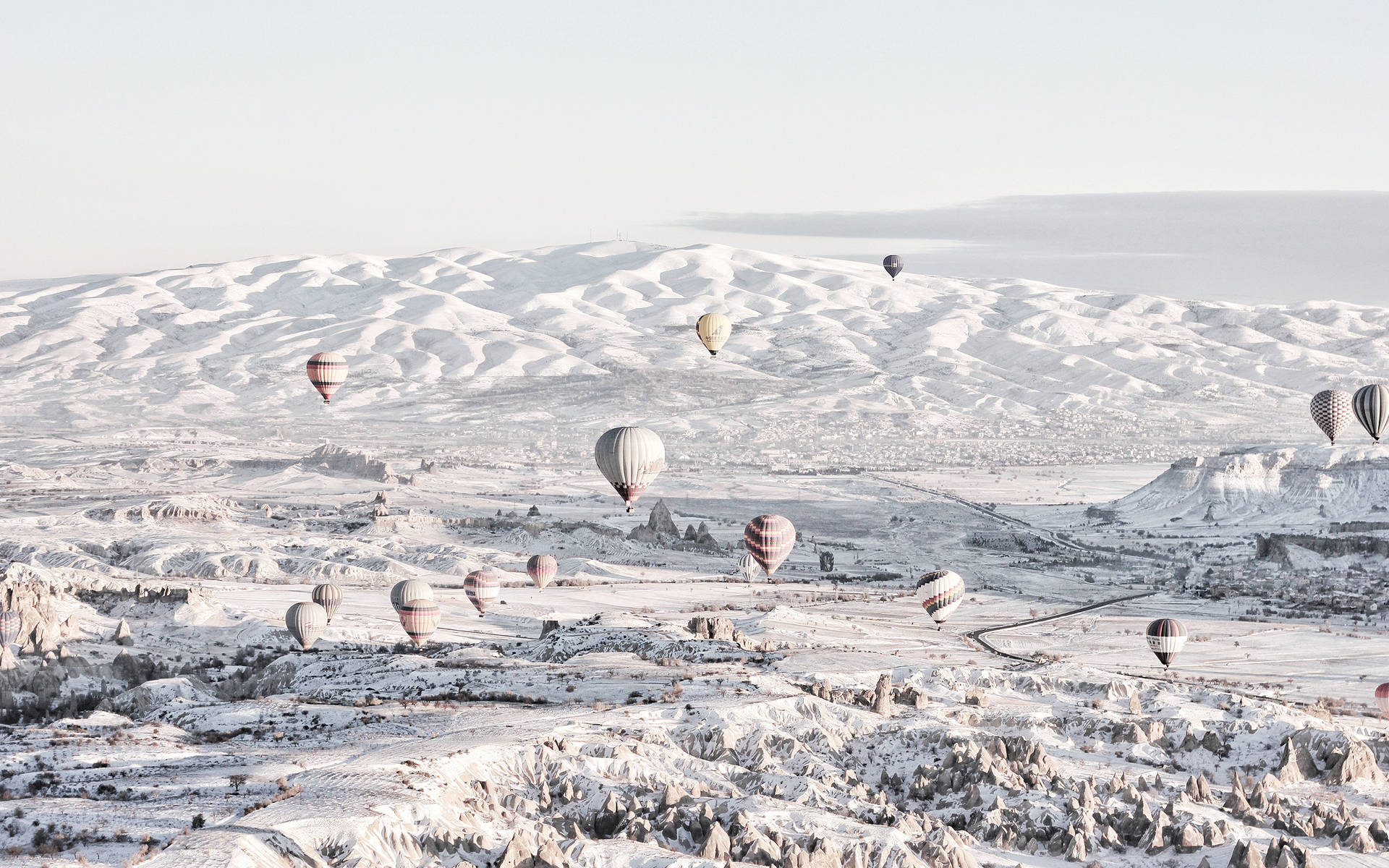 熱氣球漂浮在白雪覆蓋的山區上空。