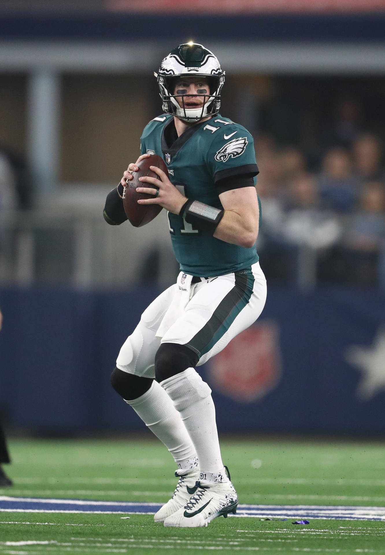 卡森·溫茲 NFL 瞬間快照 壁紙 — 費城老鷹隊四分衛身穿綠色和白色球衣，在體育場燈光下的夜間足球比賽中準備投球。