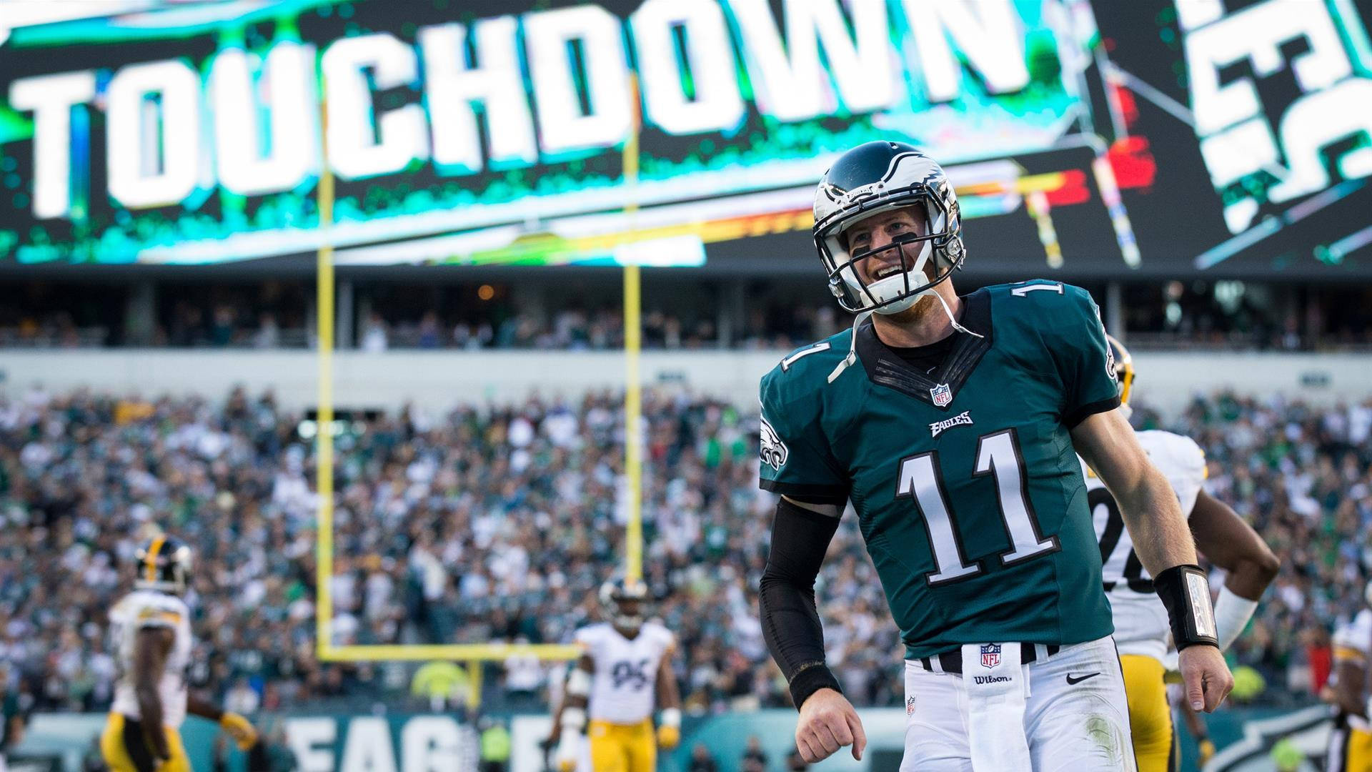 卡森·溫茲 NFL 觸地得分 壁紙 — 費城老鷹隊四分衛在球場燈光下慶祝達陣，背景有球迷歡呼。