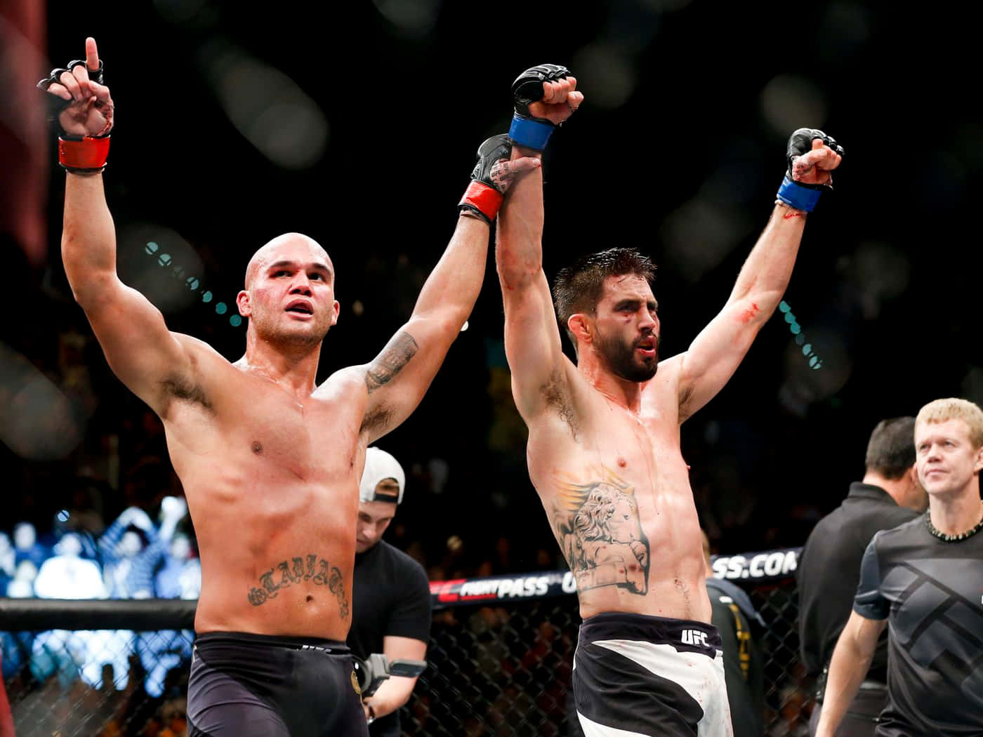 兩位赤裸上身的MMA拳手在八角籠內高舉雙臂慶祝勝利。
