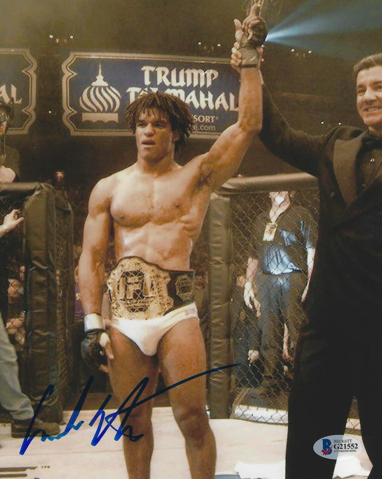 MMA拳手在八角籠中舉臂慶祝勝利。