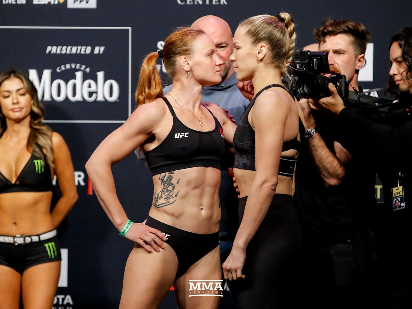 卡特琳·丘卡吉安的激烈對峙 壁紙 — 兩位女性MMA拳手在稱重活動中，在周圍閃爍的相機燈光下，進行緊張的賽前對視。