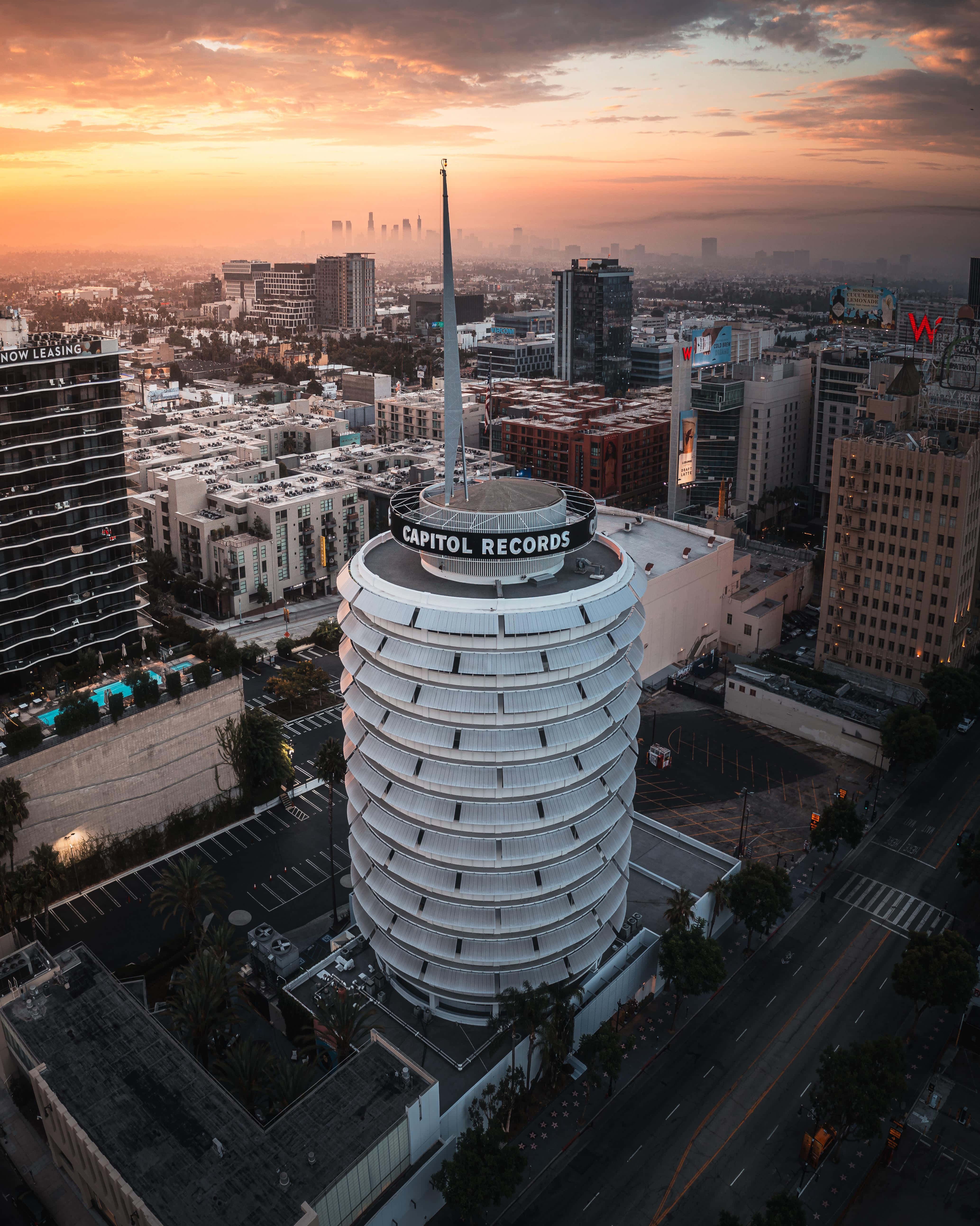卡皮托爾唱片大樓的完美視角 壁紙 — 標誌性的 Capitol Records 大樓在日落時分的鳥瞰圖，溫暖的橙色天空和下方的城市景觀。