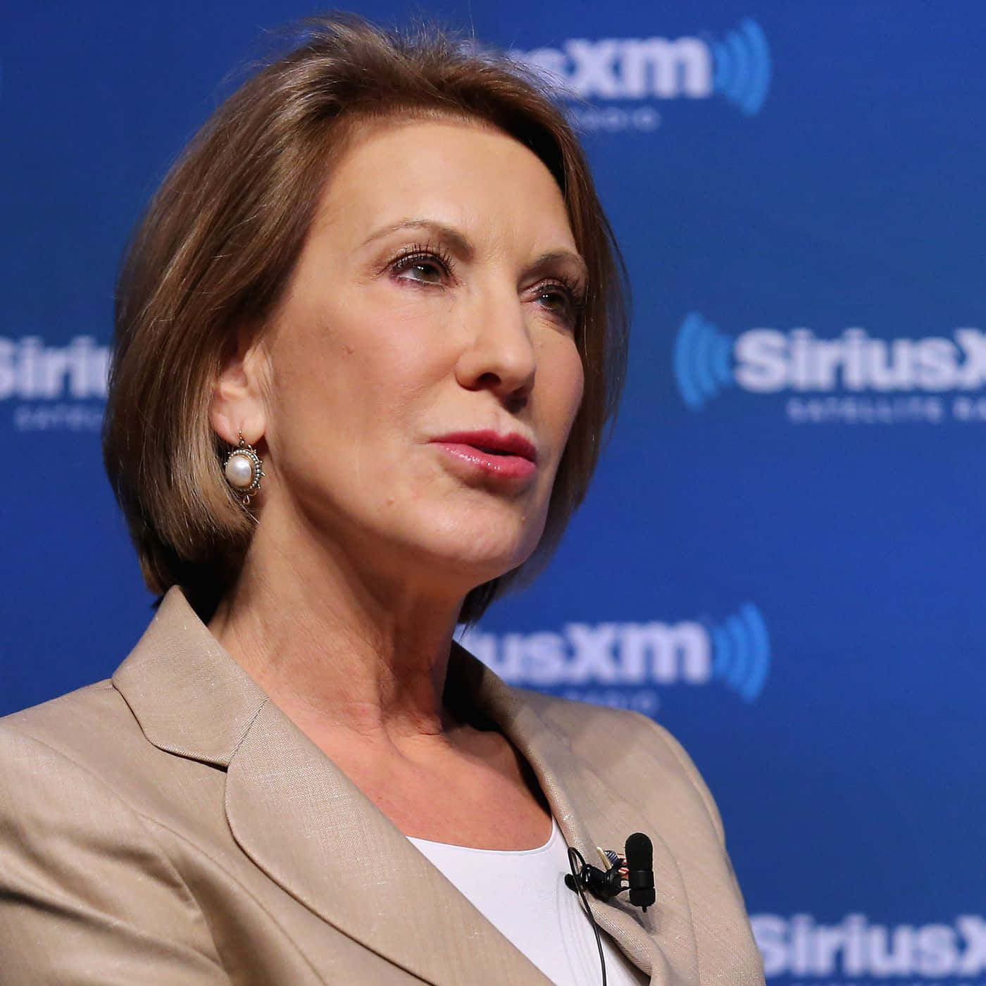 在SiriusXM活動中，身穿米色西裝外套、戴珍珠耳環的女性。