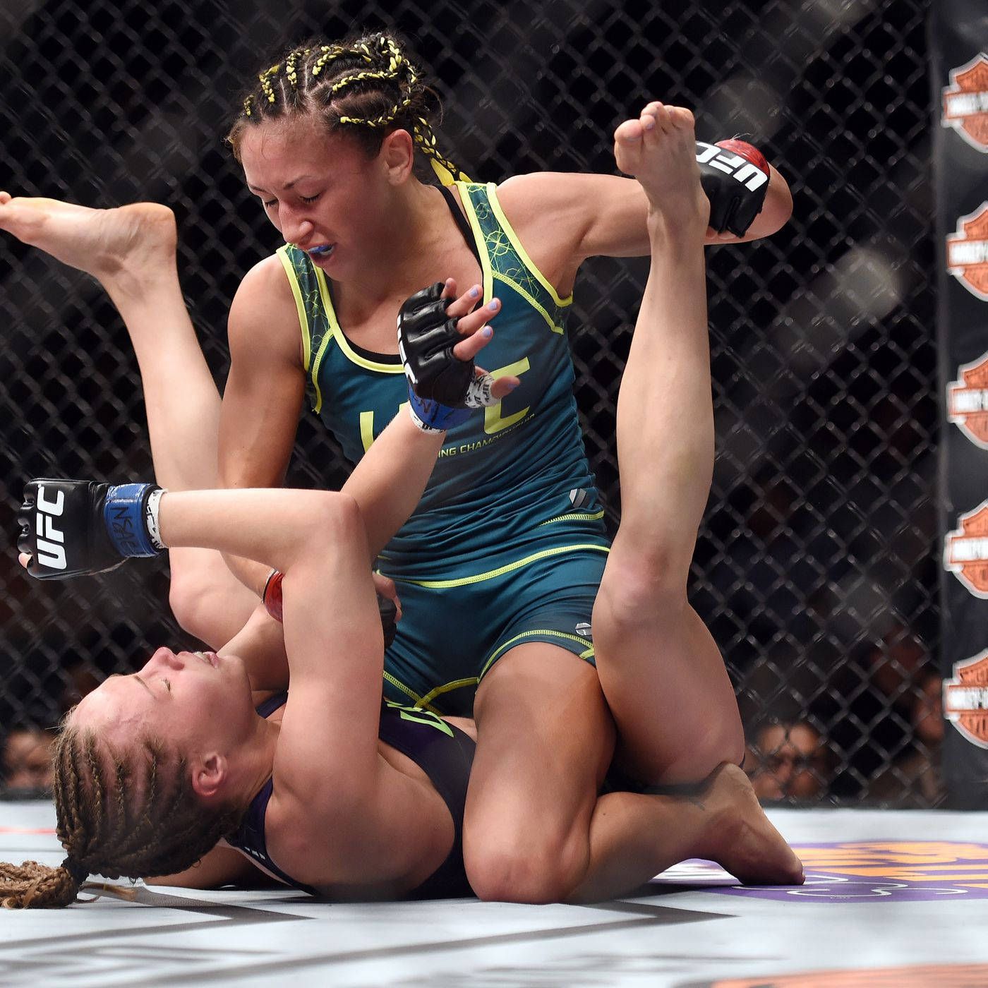 卡菈·艾斯帕薩壓制對手 壁紙 — 兩名女性MMA拳手在籠內地板上激烈糾纏，一人施展腳鎖，另一人以強烈決心防守。