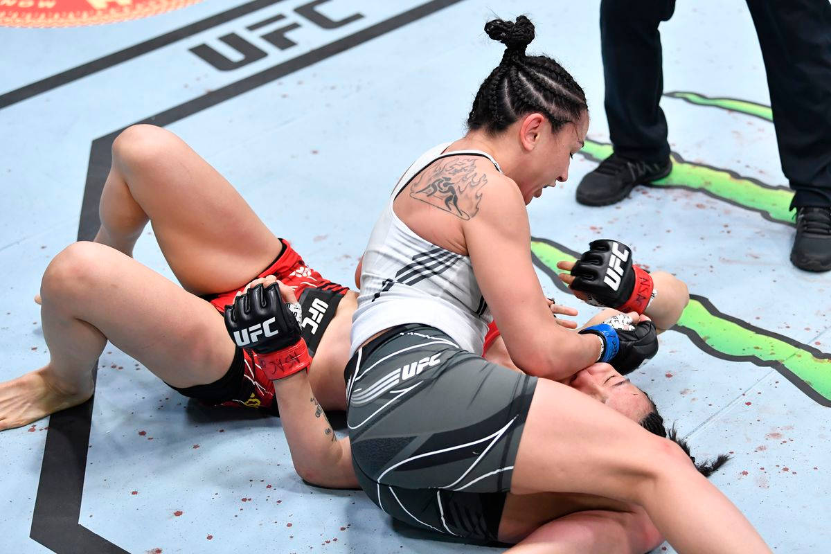 卡菈·艾斯帕薩對戰嚴小楠 壁紙 — 兩名女性MMA拳手在UFC八角籠墊上激烈纏鬥，可見血跡斑斑。