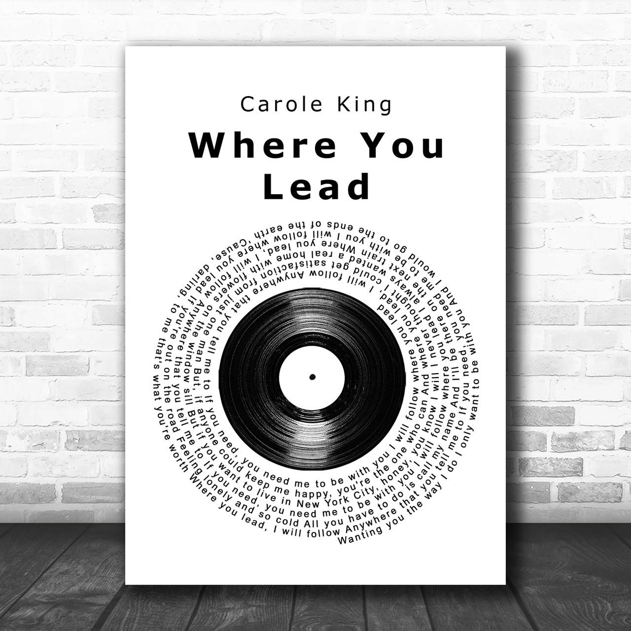 卡蘿·金《你引領的方向》 壁紙 — Carole King 的《Where You Lead》極簡黑白海報，歌詞圍繞黑膠唱片形成圓圈，安裝在白色磚牆上，下方是深色木地板。