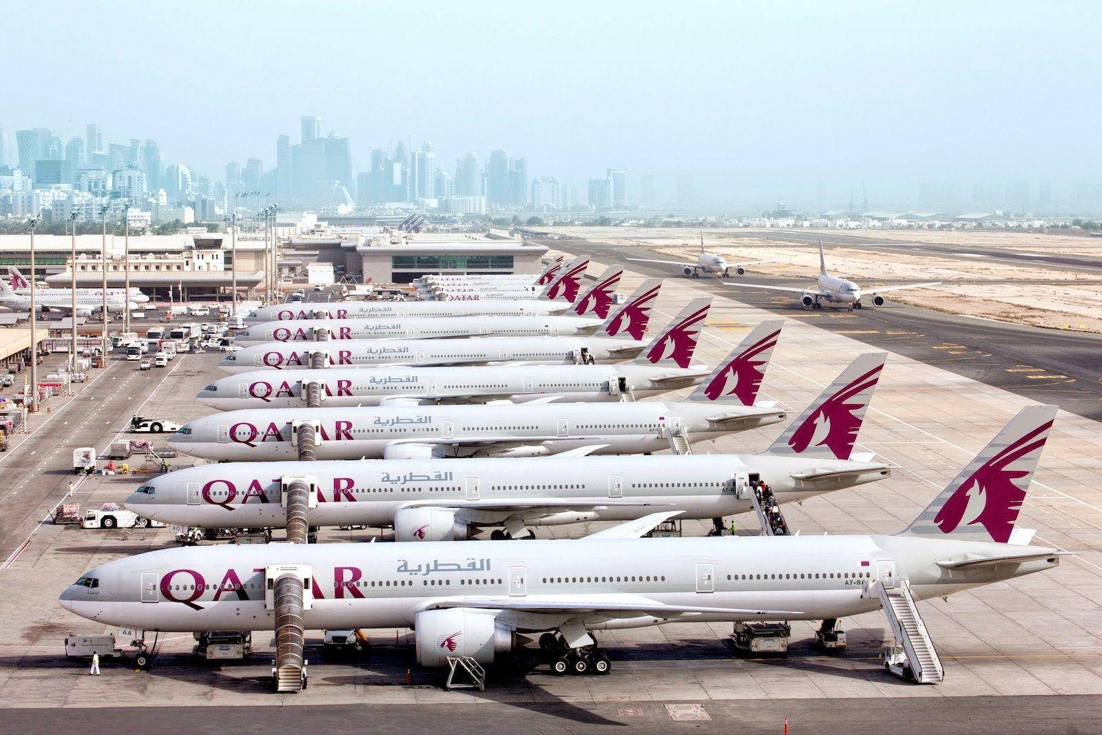 卡達航空飛機 壁紙 — 一排卡塔爾航空飛機停泊在機場閘口，背景是現代化的城市天際線。