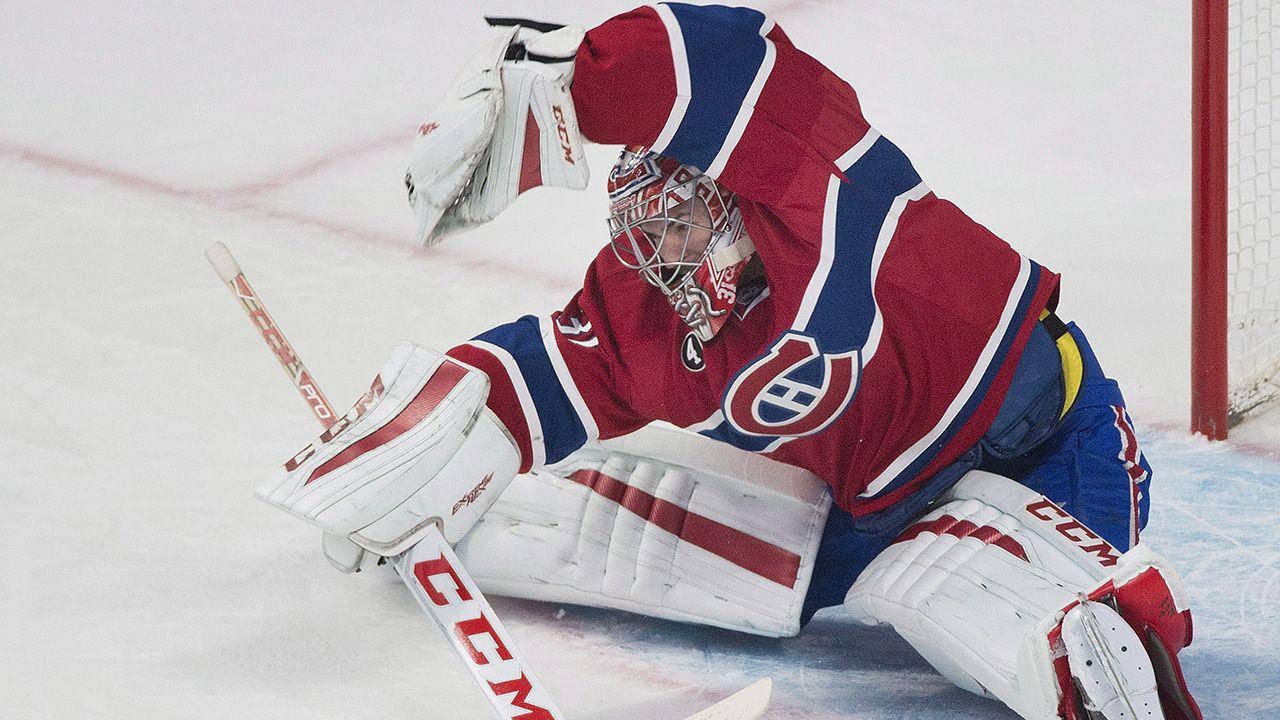卡里·普萊斯 冰球 NHL 門將 防守球門攝影 壁紙 — 蒙特利爾加拿大人隊的冰球守門員穿著紅、藍、白色裝備在冰上做出戲劇性的撲救。