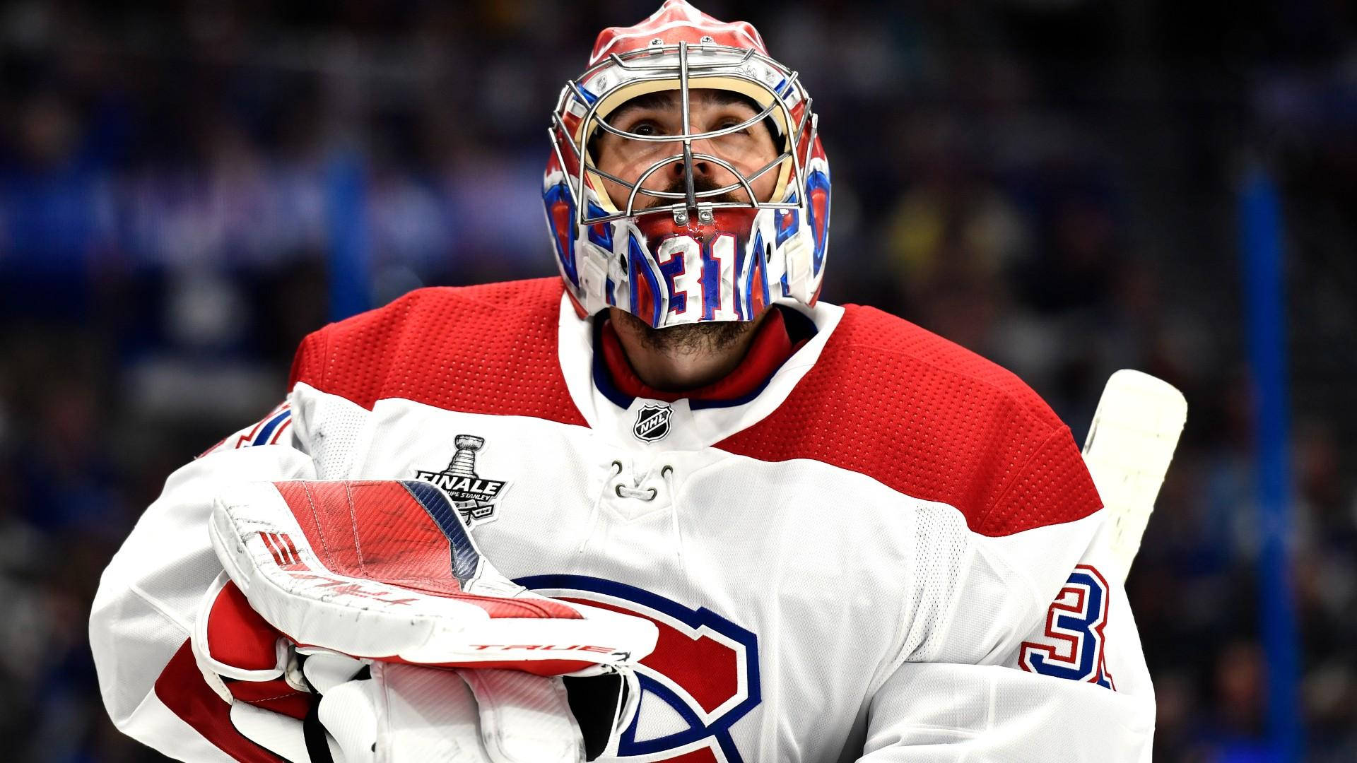 卡里·普萊斯NHL冰球蒙特利爾加拿大人隊攝影 壁紙 — 一位專注的曲棍球守門員，身穿紅、白、藍色裝備，在明亮的場館燈光下於比賽中握著球桿。