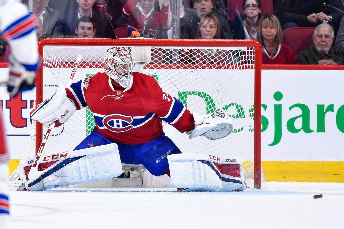 卡里·普萊斯NHL門將擋球攝影 壁紙 — 一位蒙特利爾加拿大人隊的守門員穿著紅、藍、白色裝備，在激烈的冰球比賽中低蹲在球門前，背景有觀眾。