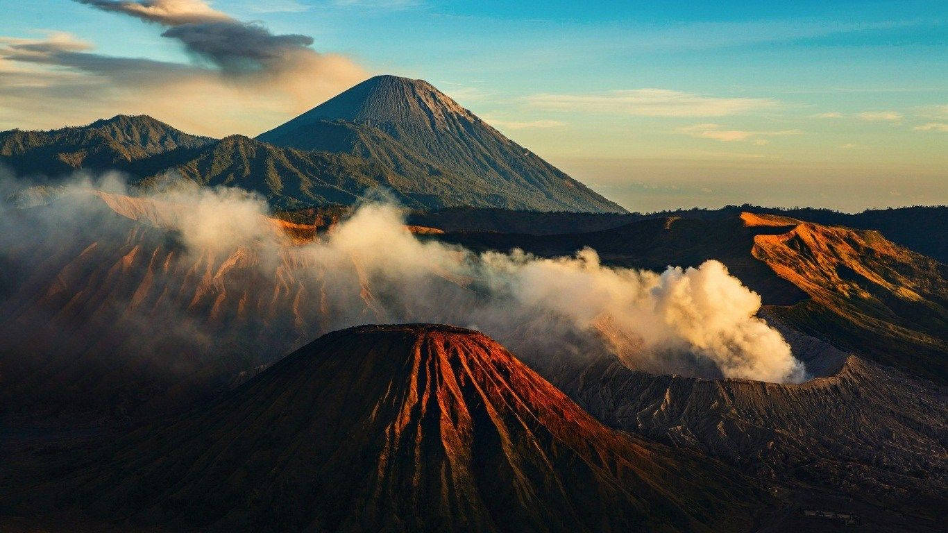 日出時火山升起蒸氣的山脈