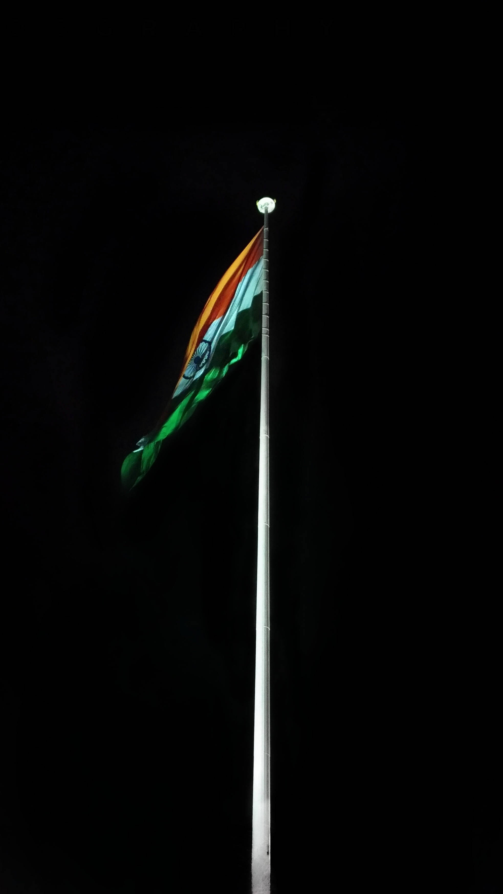 India 桌布 壁紙 — 印度國旗在夜晚漆黑的天空中在高高的旗桿頂端飄揚。