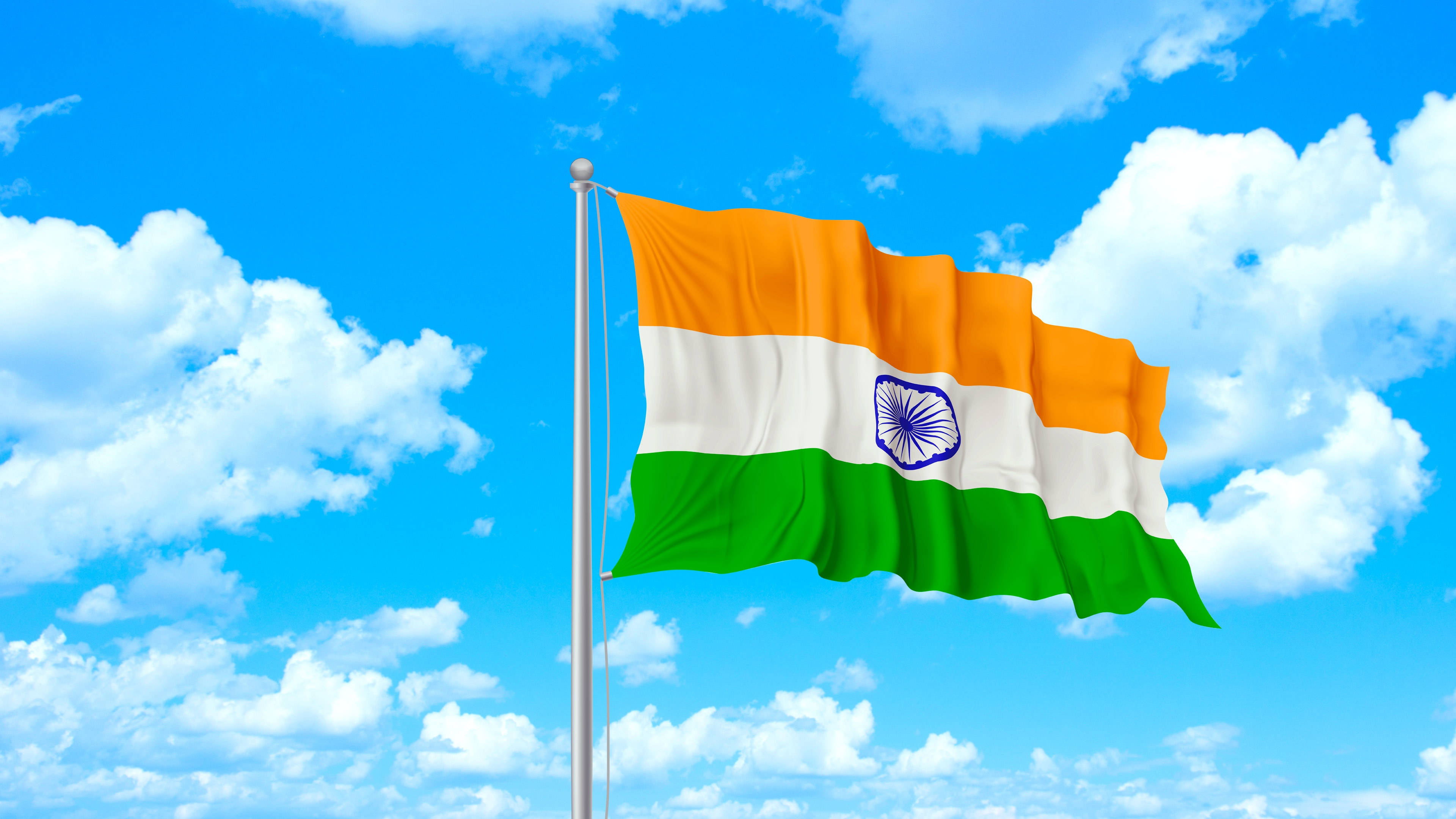 Indian 桌布 壁紙 — 印度國旗在旗桿上自豪地飄揚，背景是明亮的藍天，充滿蓬鬆的白雲。