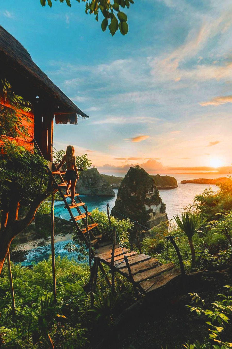 人在日落時分從樹屋爬上木梯欣賞海景