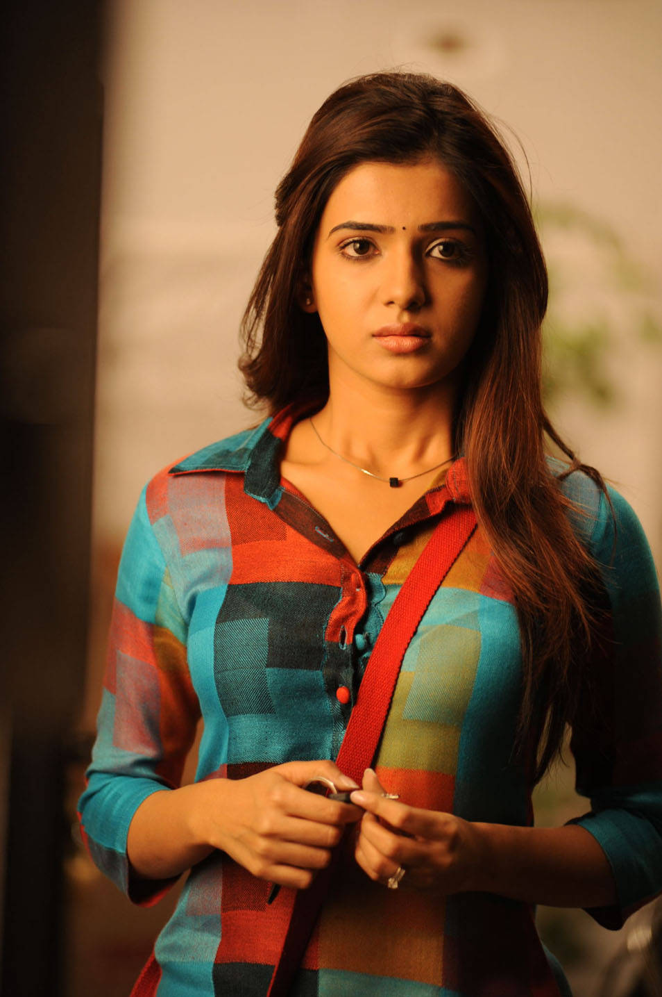 印度影星阿克金尼·薩曼莎 HD 壁紙 — 一位長黑髮的年輕女性穿著彩色格紋襯衫，手持紅色帶子，直視鏡頭。
