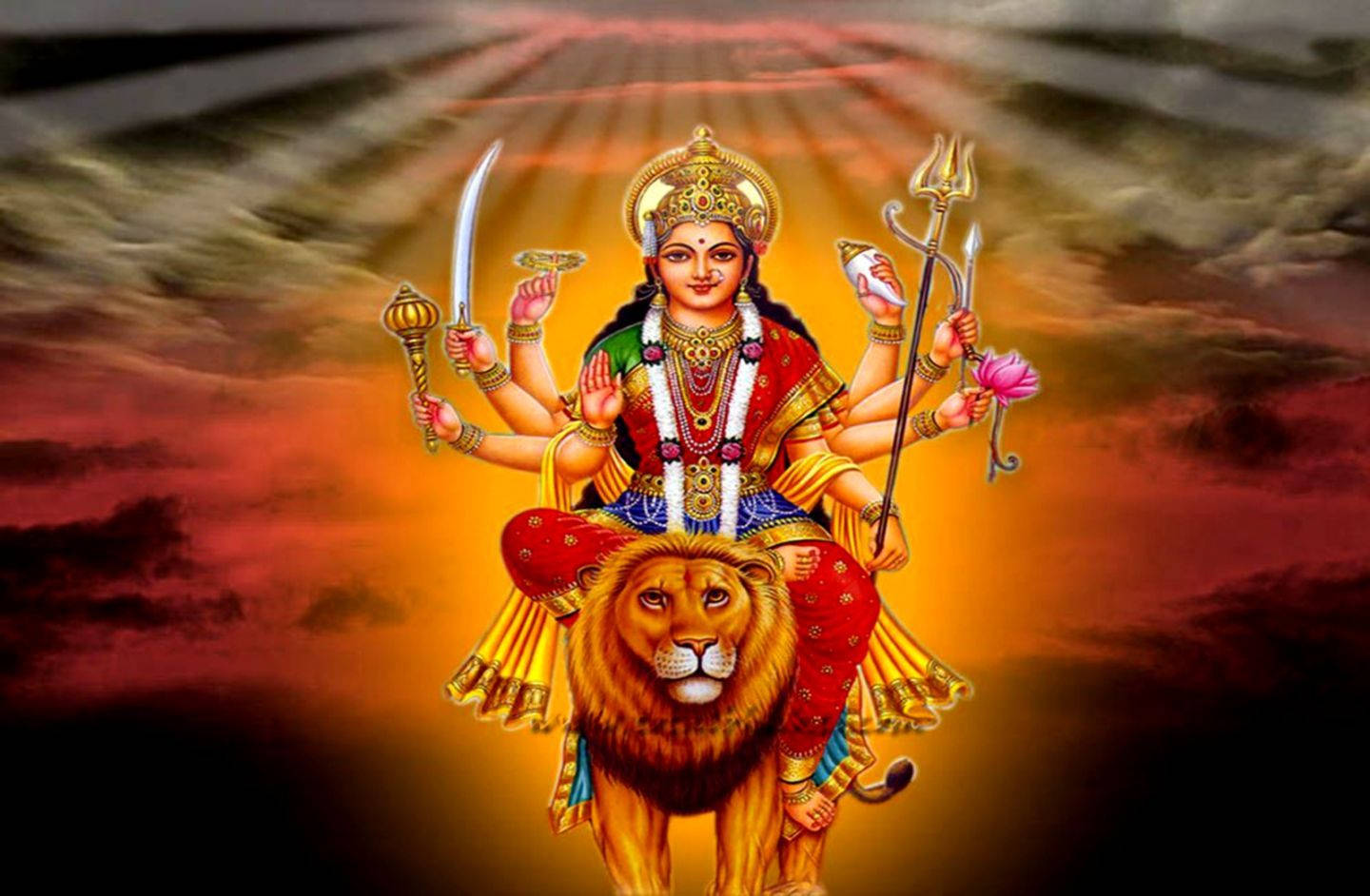 多臂印度教女神騎著獅子，背景是熾熱的日落天空。 — 神 壁紙