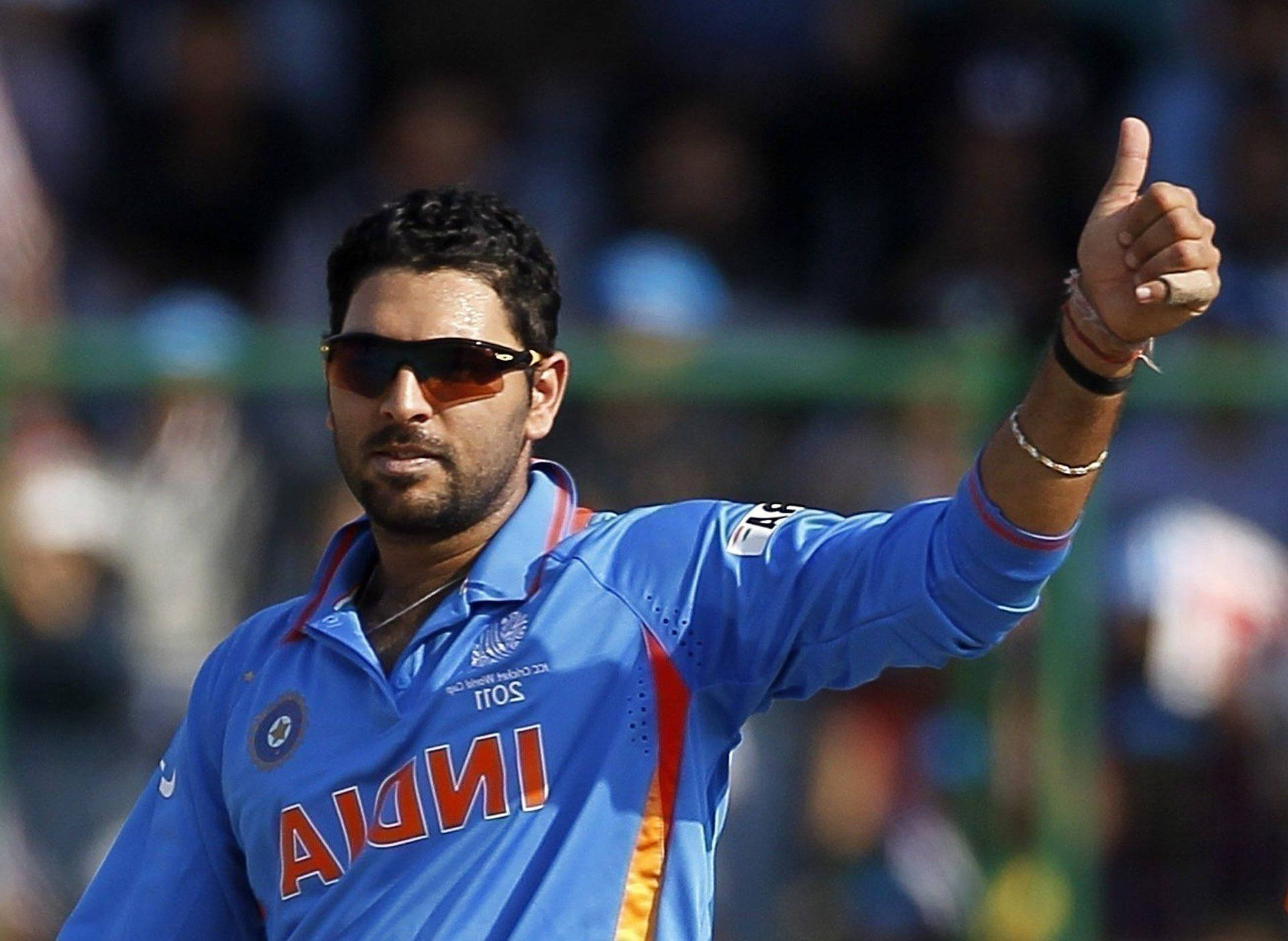 板球運動員身穿藍色球衣，戴著太陽眼鏡做出豎起大拇指的手勢。 — 印度板球 壁紙