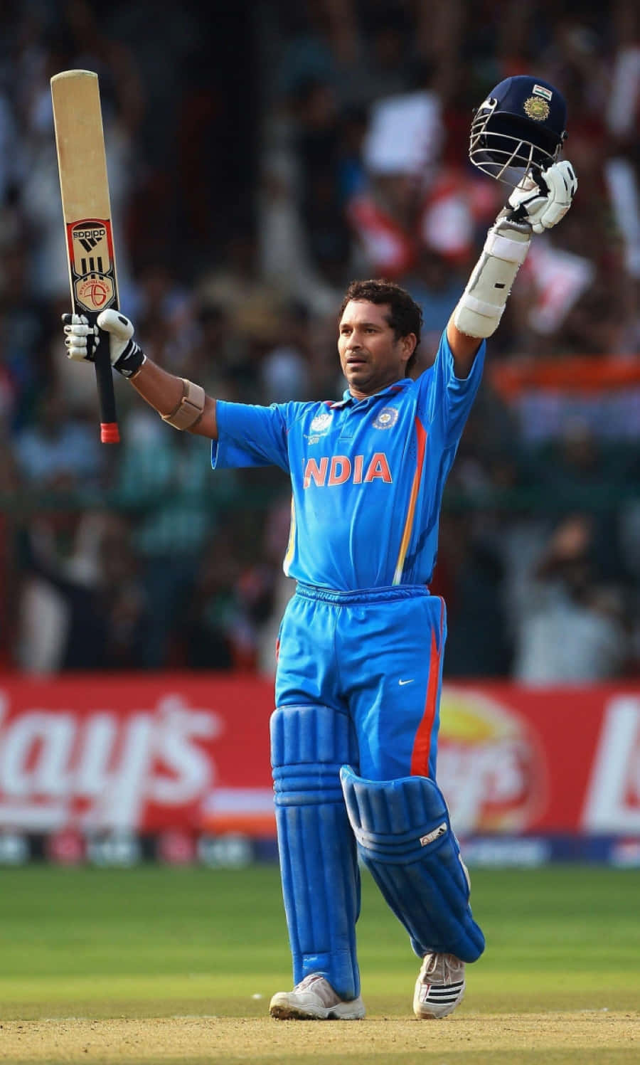 Sachin Tendulkar 桌布 壁紙 — 印度板球隊隊長在球場上慶祝勝利，身穿藍色制服，高舉球棒和頭盔。
