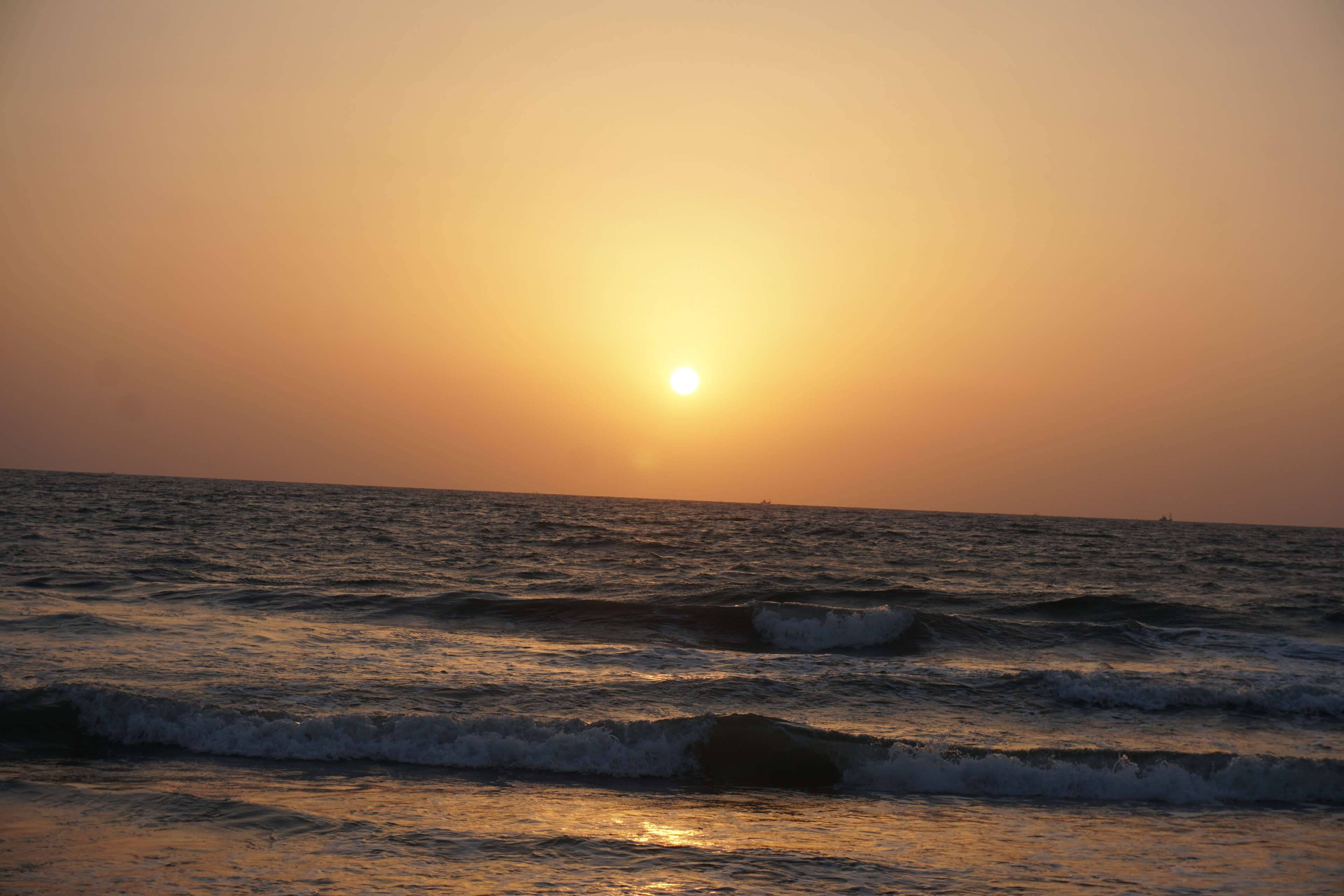 印度果阿日落 壁紙 — 金色夕陽沉入地平線下，在平靜的日落中為翻滾的海浪投下溫暖的光芒。