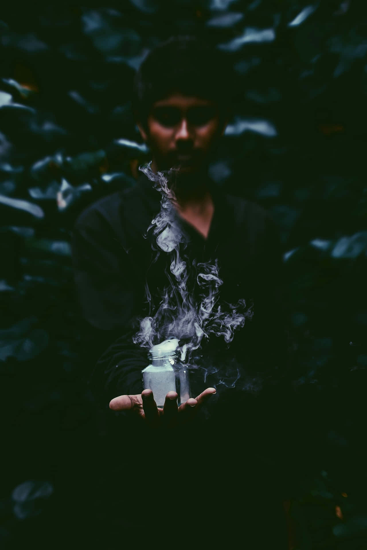 在黑暗森林中手持冒煙罐子的人，背景有樹葉