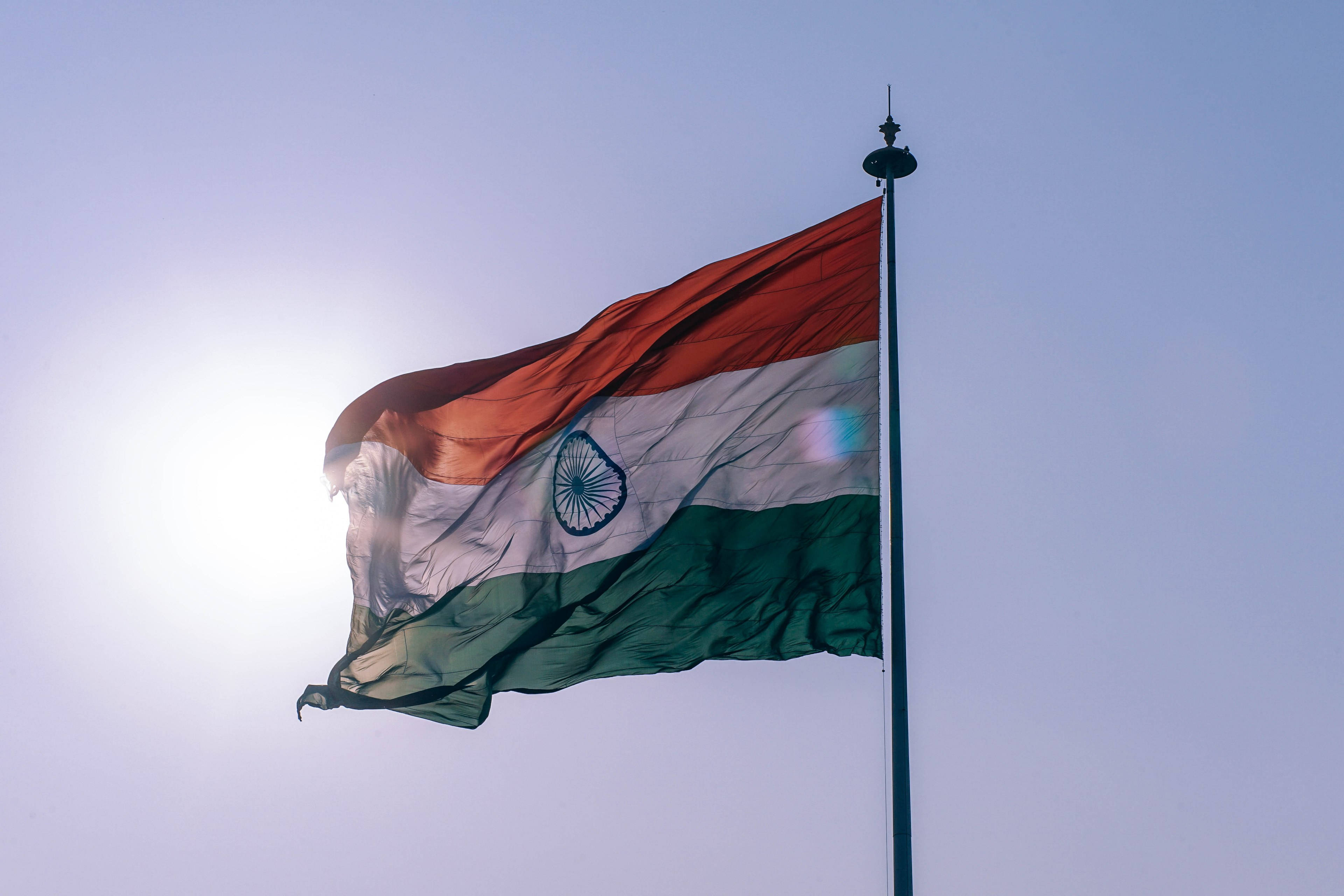 Indian 桌布 壁紙 — 印度的三色旗在明亮的陽光天空下自豪地飄揚，帶有鏡頭光暈。