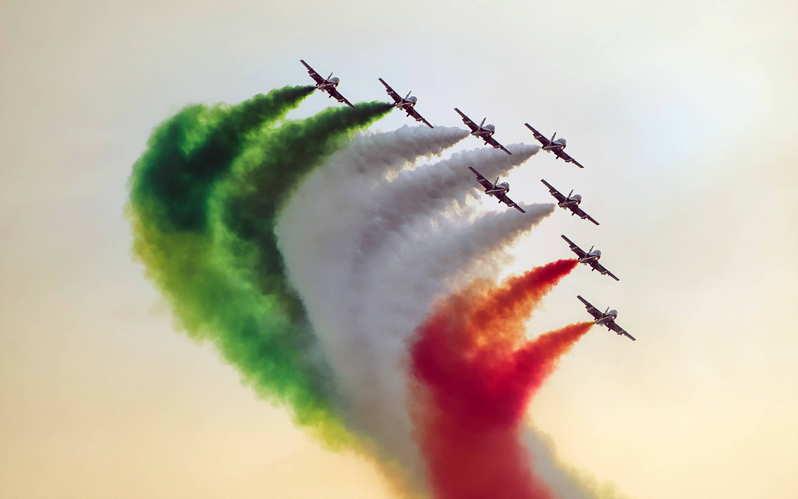 印度空軍 壁紙 — 九架戰鬥機以緊密編隊飛行，釋放出綠色、白色和紅色的煙霧軌跡，在朦朧的天空中形成意大利國旗。