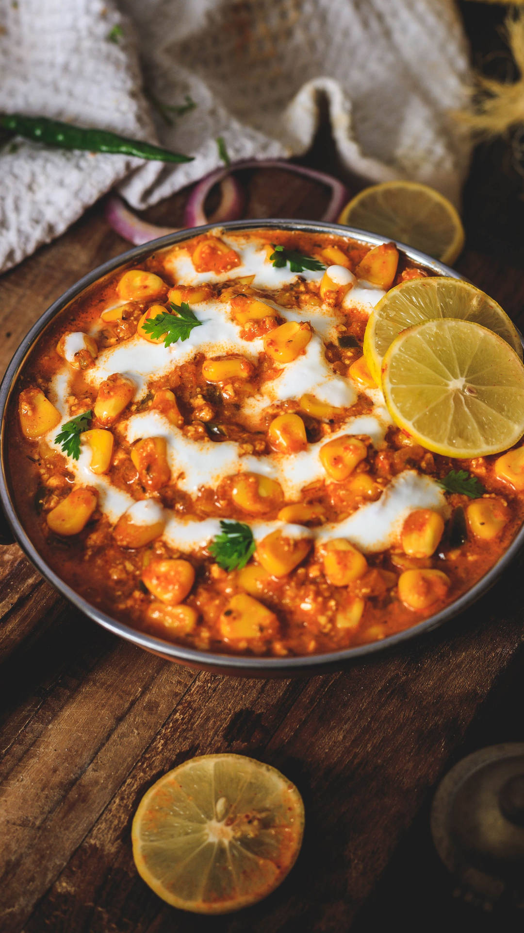 一碗chole masala，配上檸檬片和芫荽，放在木桌上。