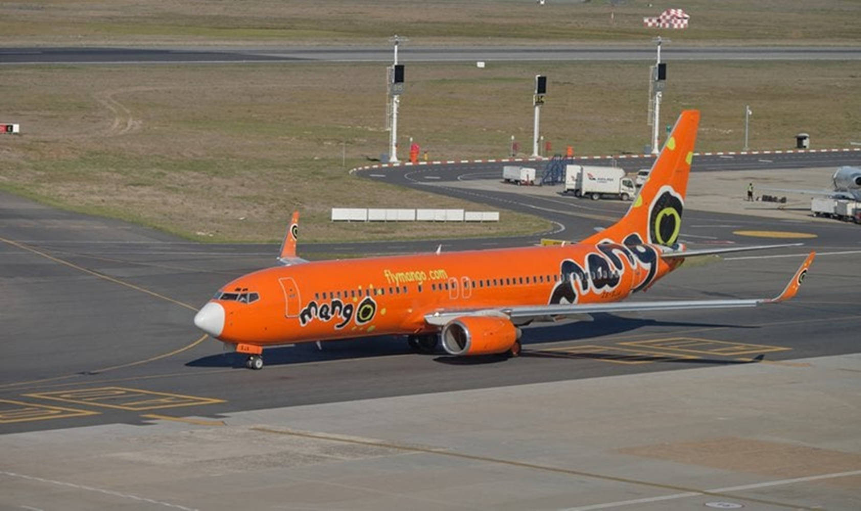 橙色Mango Airlines噴射機在日間於機場跑道滑行。
