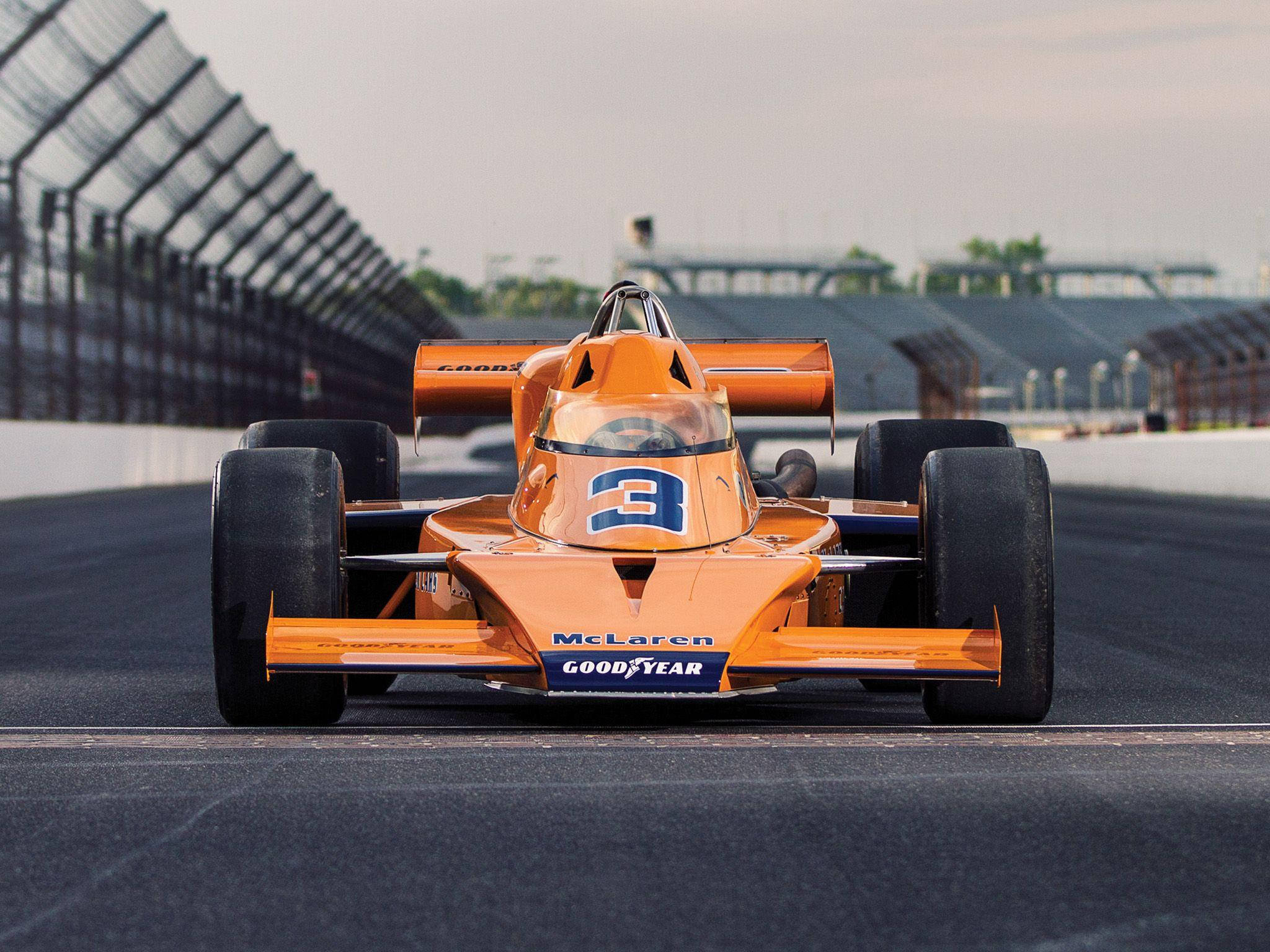 印第安納波利斯500賽事麥拉倫賽車 壁紙 — 一輛復古橙色McLaren賽車（編號3）在朦朧的天空下於賽道上飛馳。