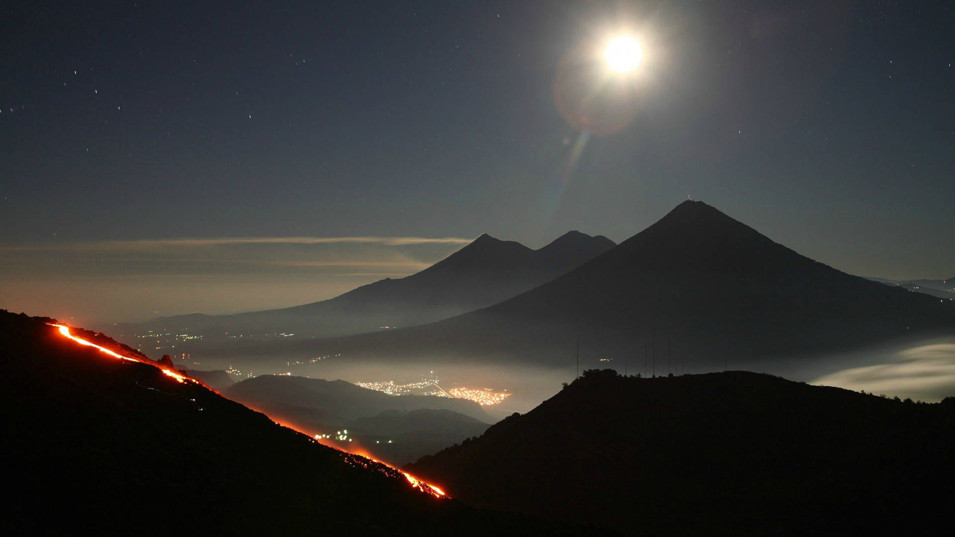 夜晚噴發的火山，發光的熔岩流和上方明亮的月亮。