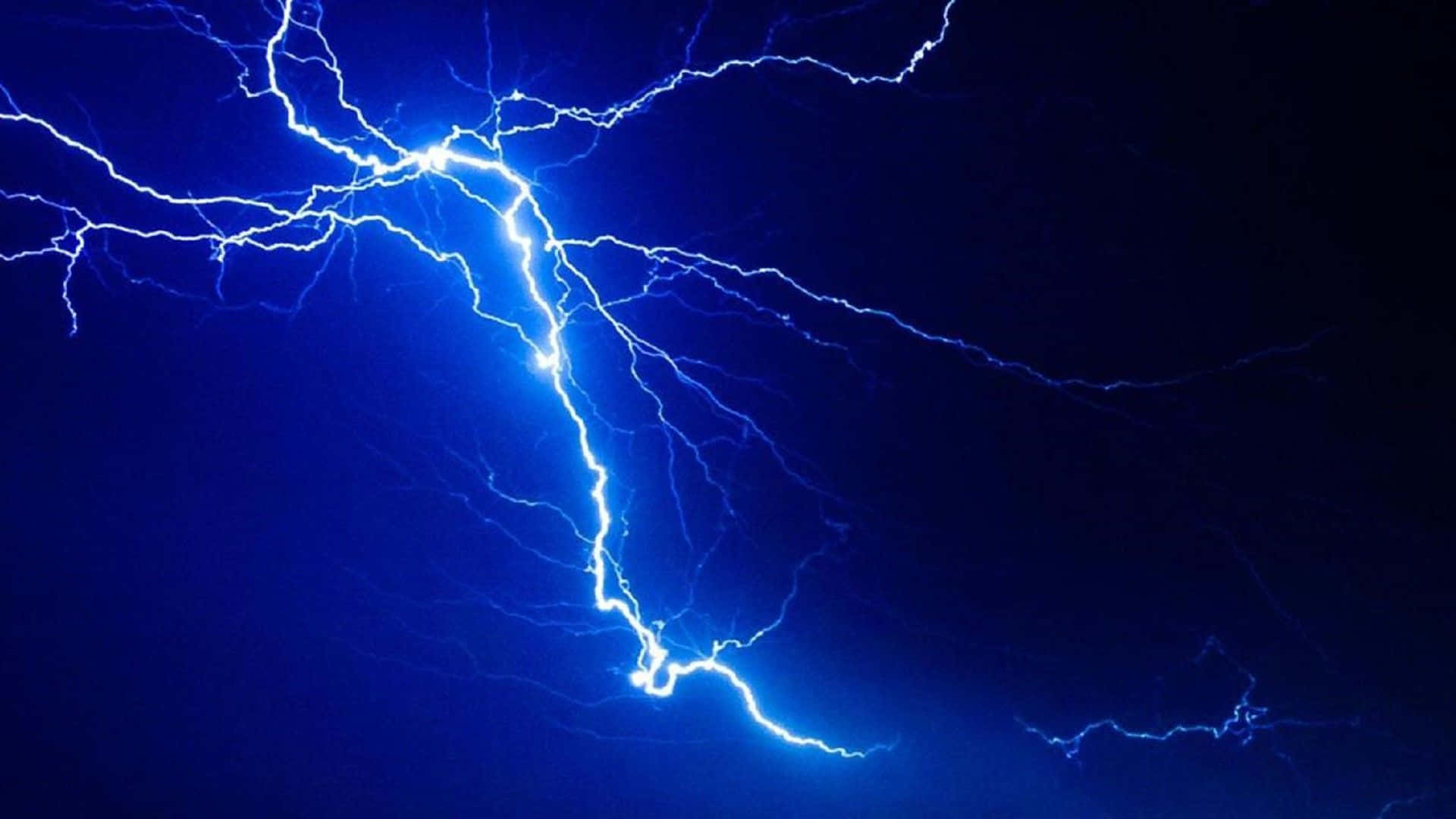 危險卻美麗——天空中的閃電 壁紙 — 一道明亮的藍色閃電在深靛藍色的夜空中分叉，呈現出戲劇性的自然景象。