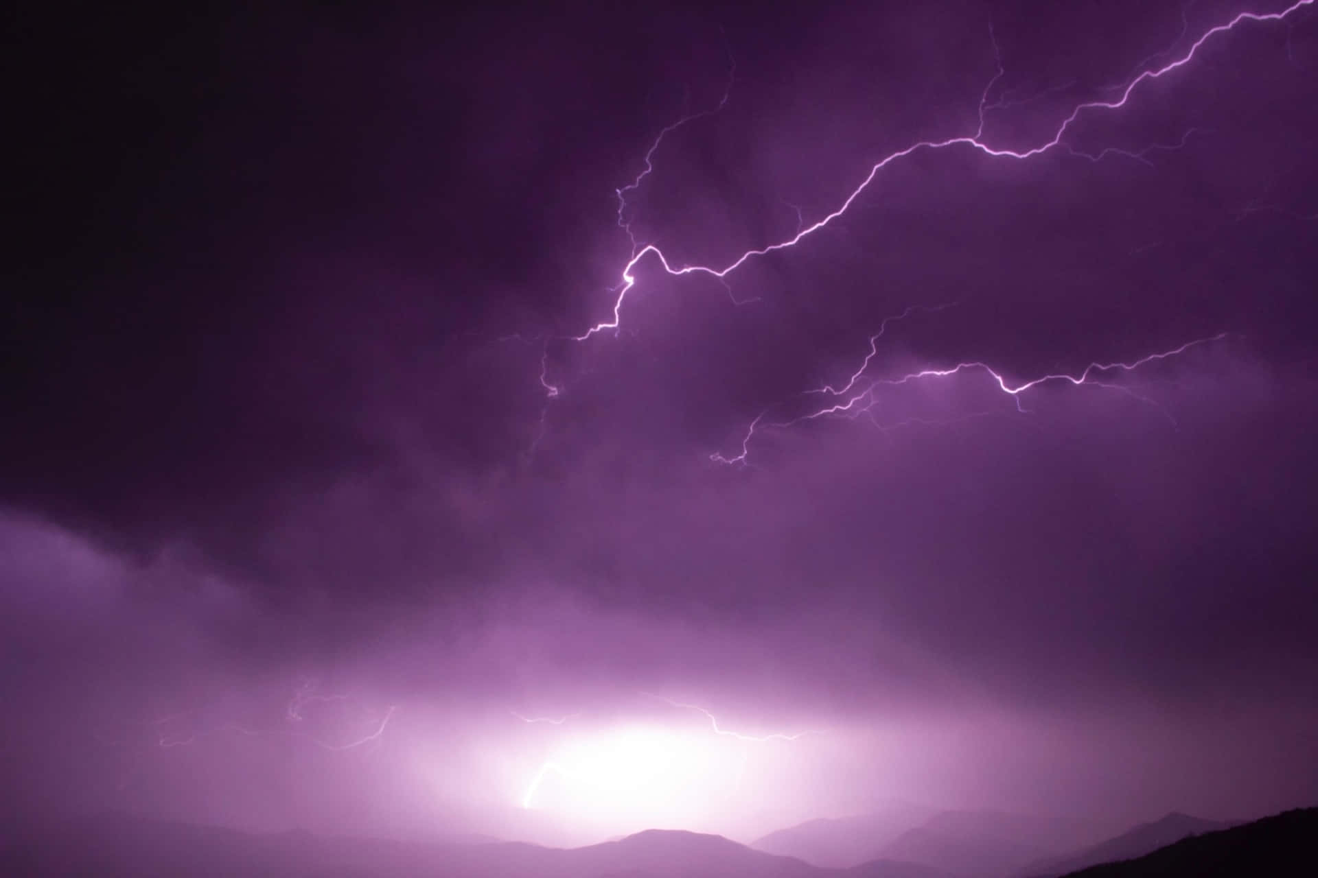 紫色閃電照亮了山脈剪影上方的暴風雨夜空。