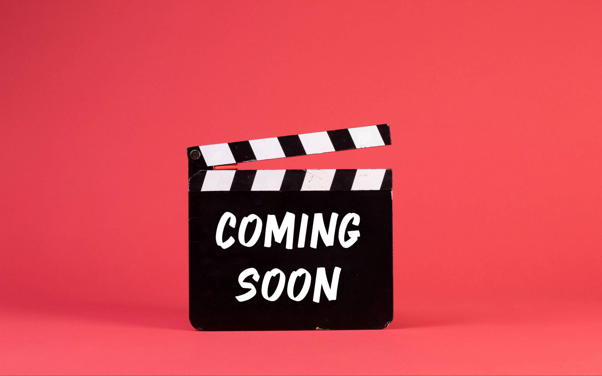 珊瑚粉紅色背景上帶有 'COMING SOON' 文字的場記板
