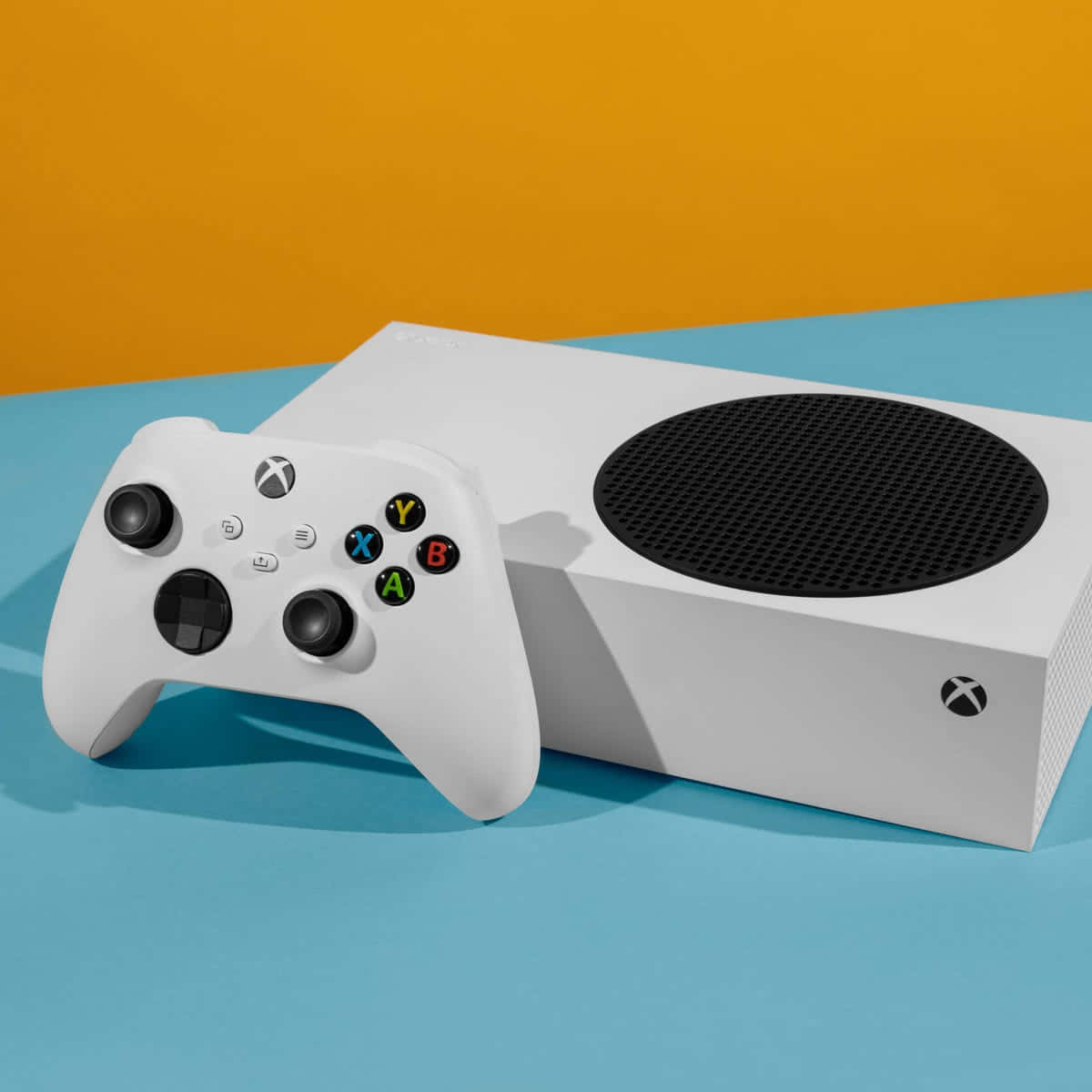 白色Xbox主機和手掣在藍色表面上，橙色背景。