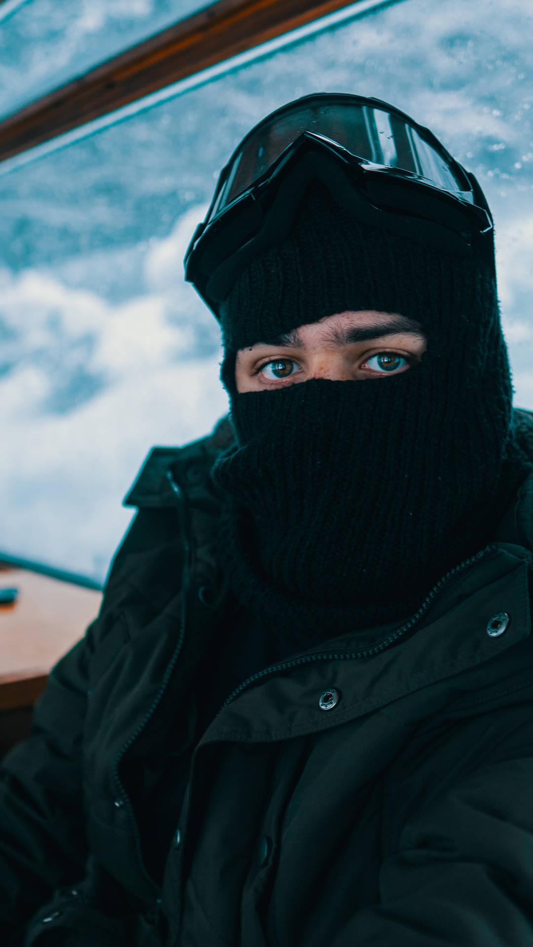 戴黑色巴拉克拉法帽和護目鏡的人望向雪窗外
