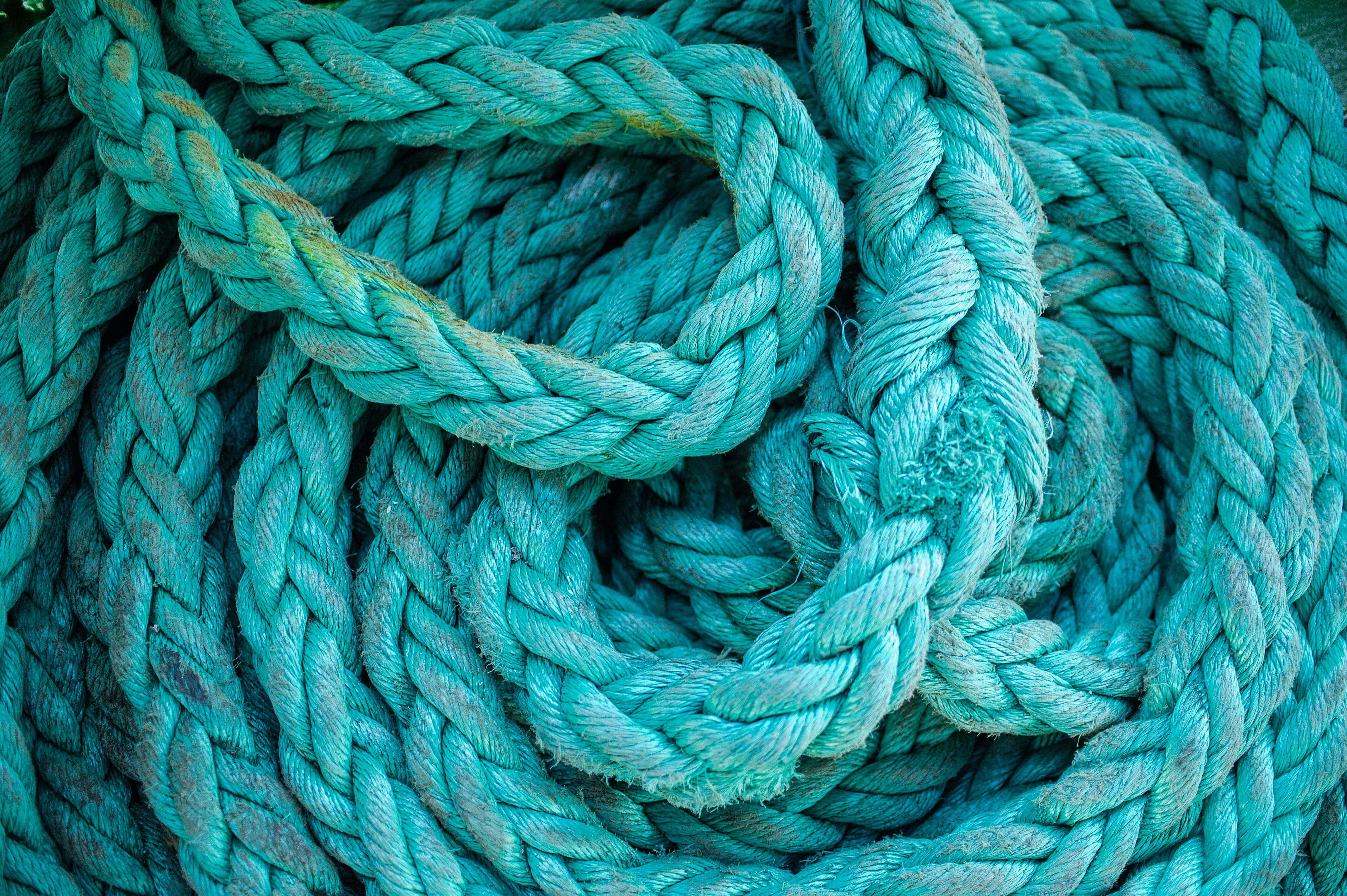 Turquoise Green 桌布 壁紙 — 厚實青綠色編織繩索的特寫，纏繞成複雜的環圈，顯示磨損的質地和磨損的纖維。
