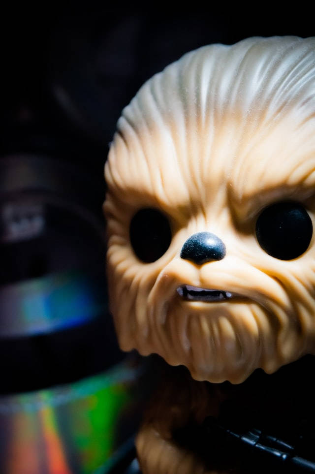 原力釋放——星際大戰靈感iPhone壁紙 壁紙 — 特寫鏡頭：Funko Pop Chewbacca 人偶，眼睛發光，毛髮有紋理，背景黑暗。