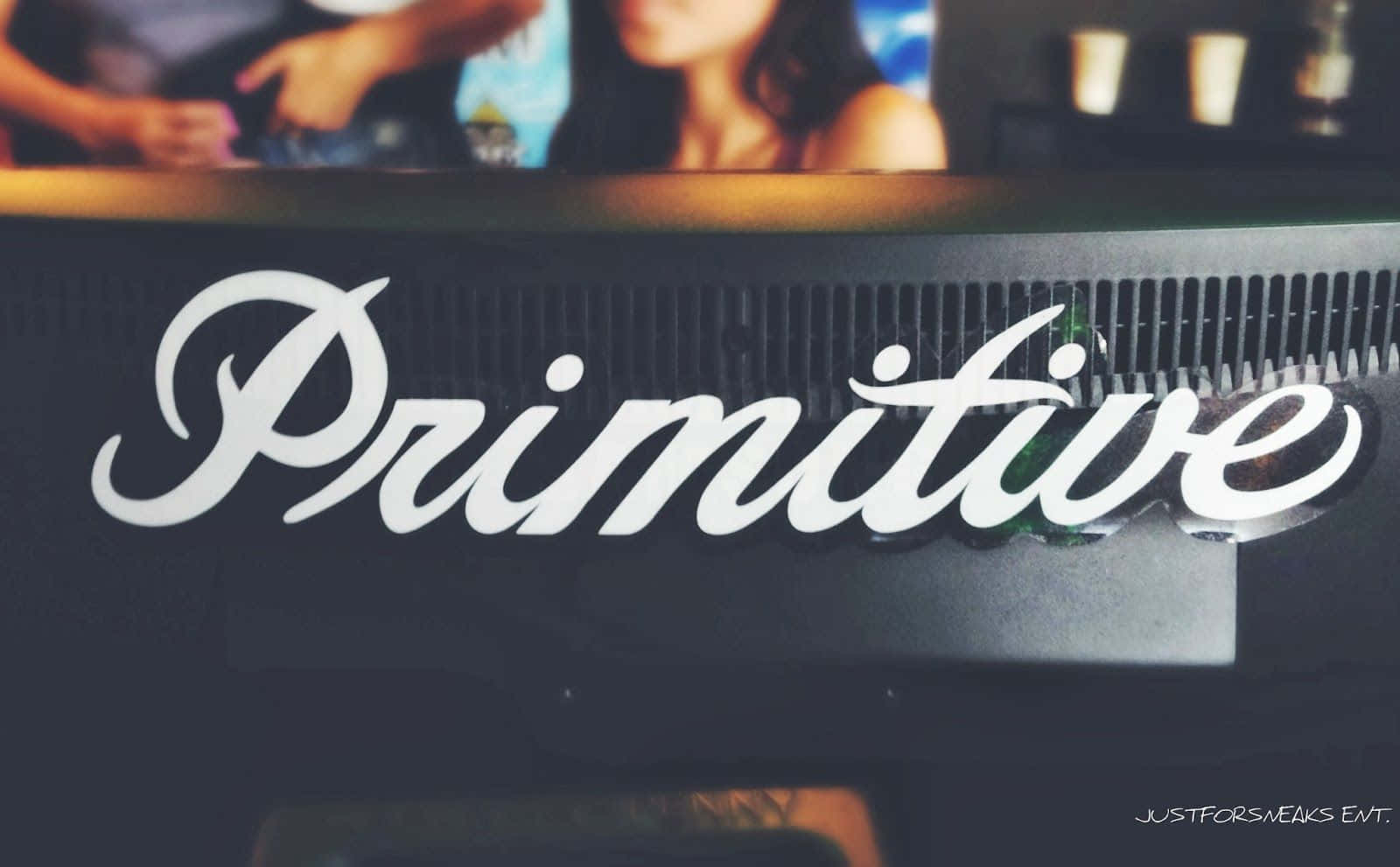 昏暗酒吧，帶有白色草書 'Primitive' 標誌，背後有模糊的顧客。