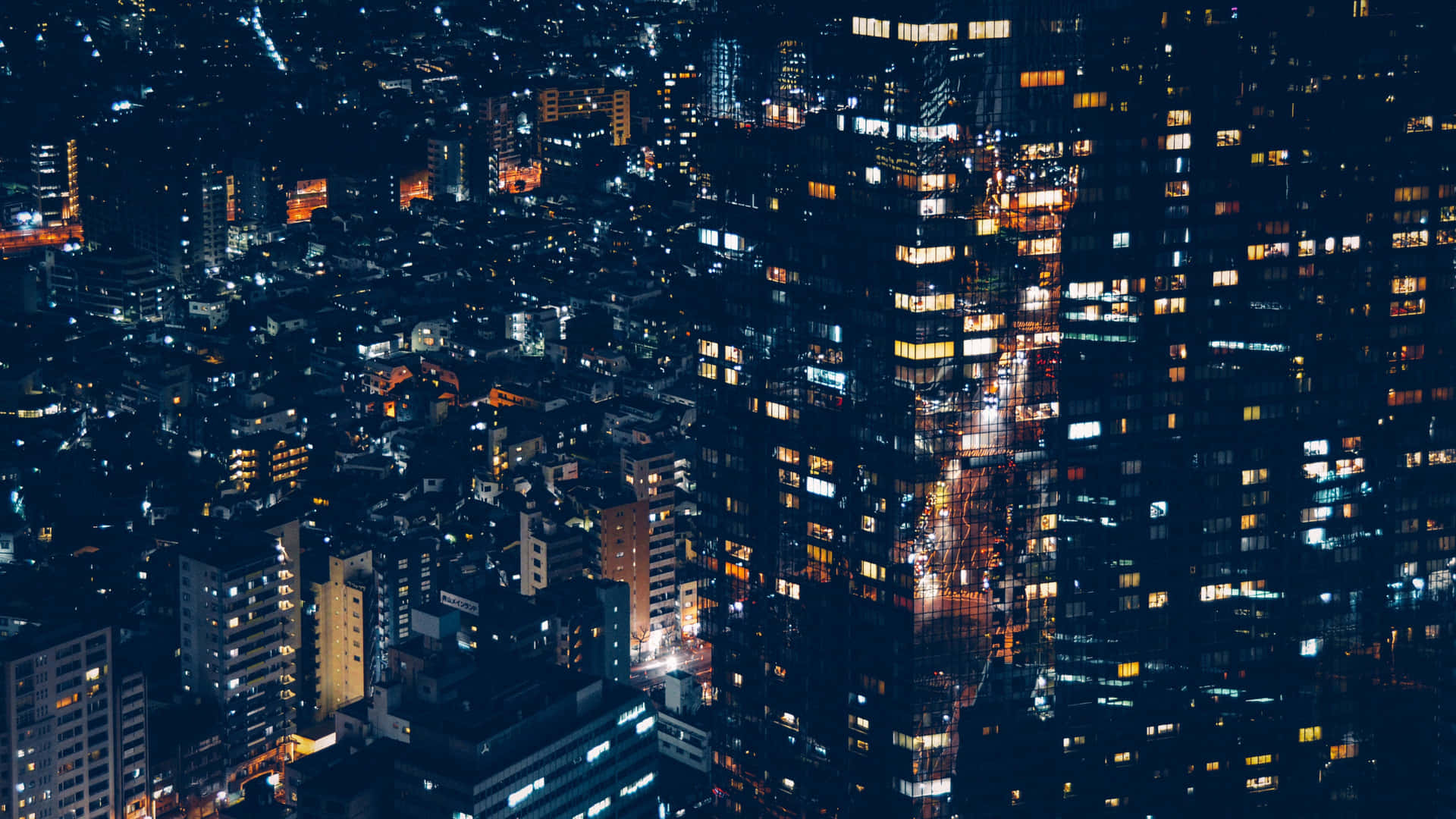 從空中視角看到的夜間城市景觀，帶有發光的窗戶和照明街道。