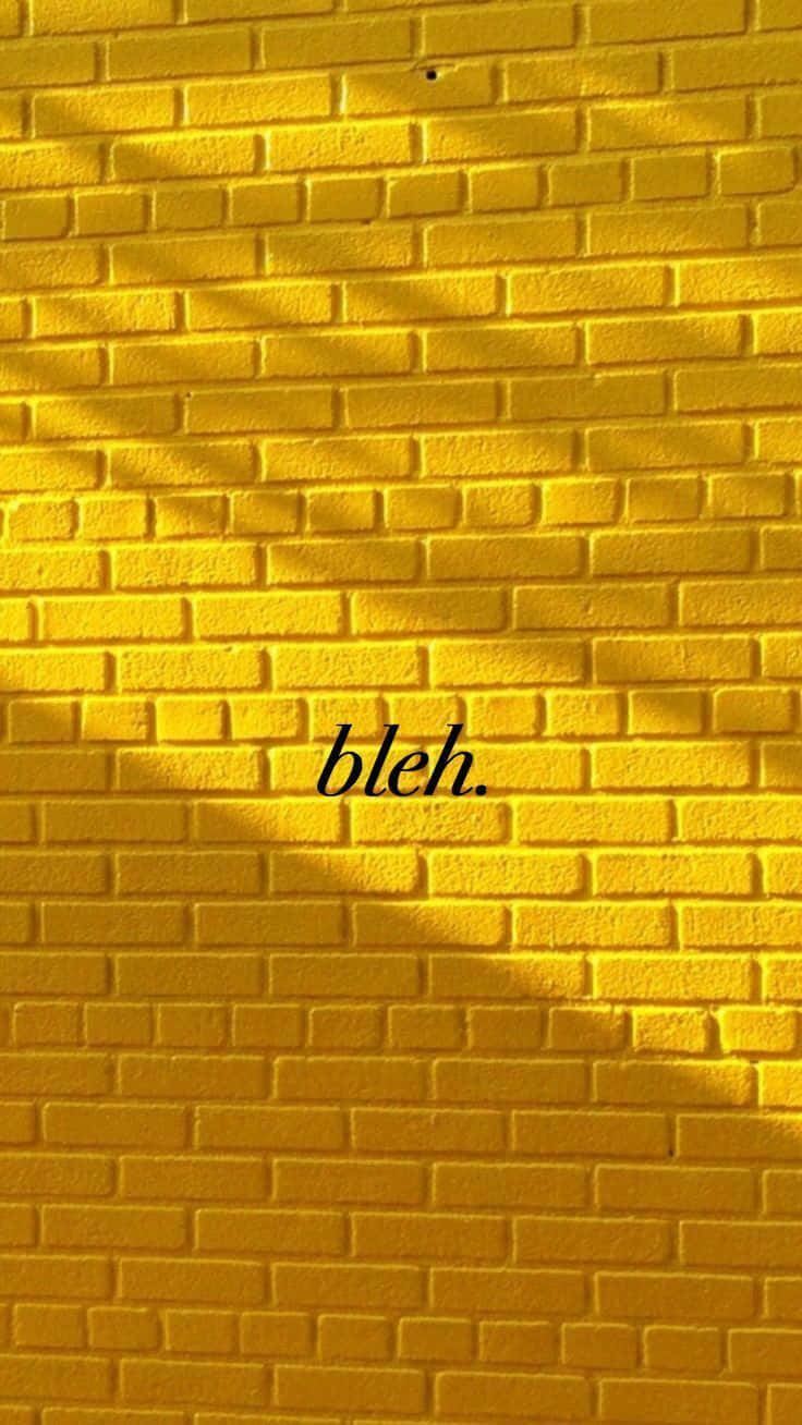 黃色磚牆，帶有樹葉陰影，並以黑色字體寫著「bleh」。