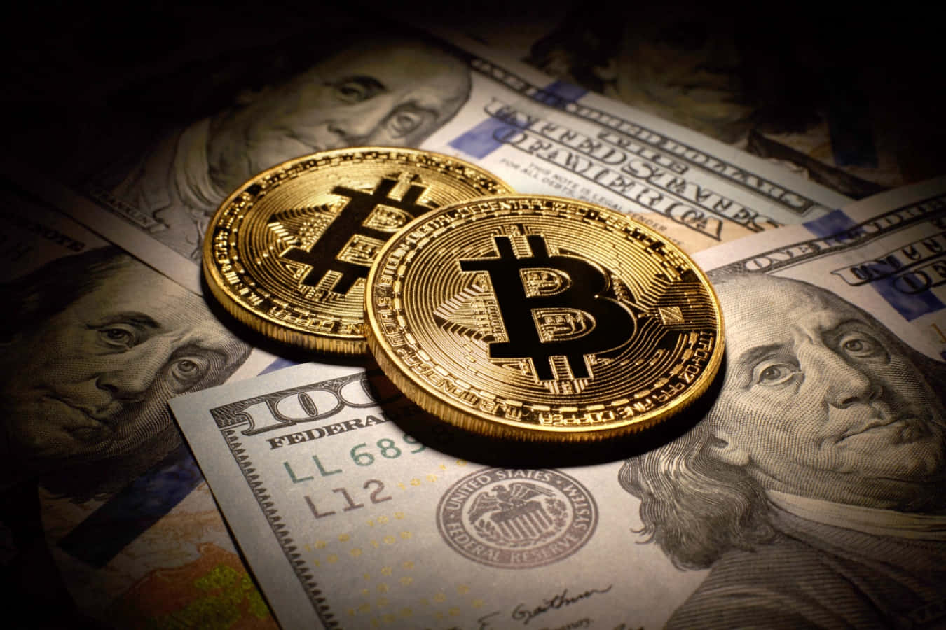 聚光燈下，兩枚金色比特幣硬幣放在美元鈔票上。 — 比特幣 壁紙