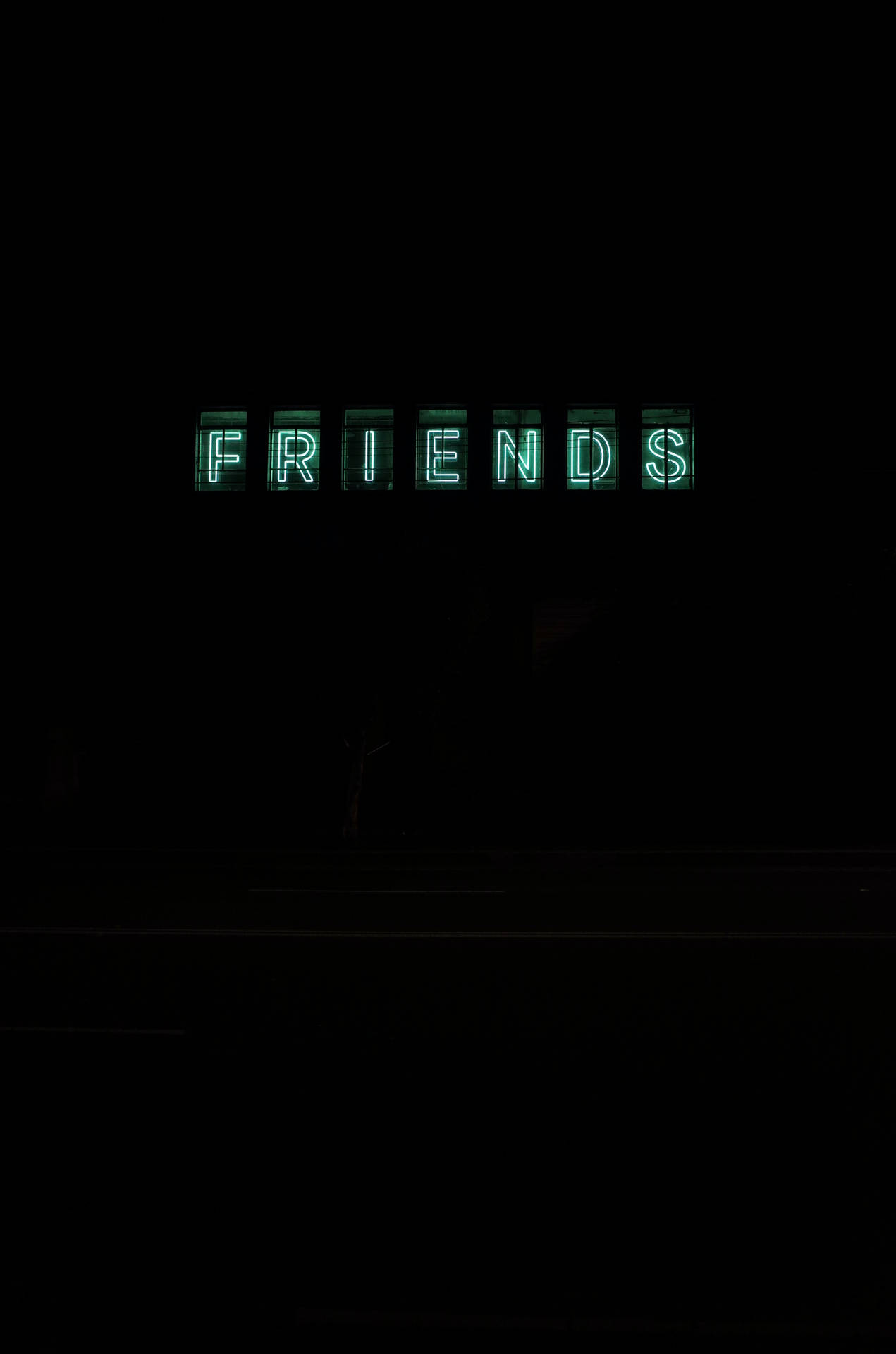 一個發光的綠色霓虹燈牌，上面寫著 FRIENDS，背景是黑暗的夜空。