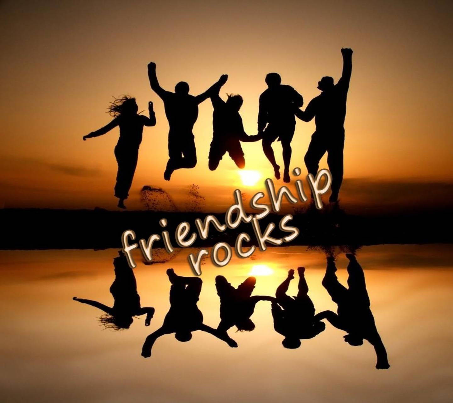 五個人在日落時以剪影跳躍，水中倒影和文字friendship rocks。