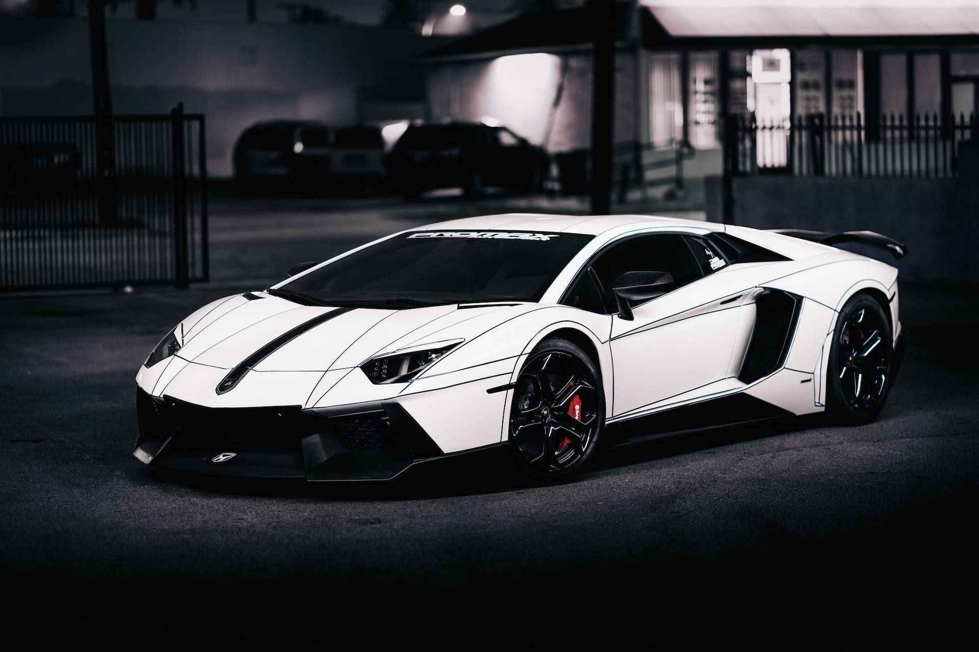 白色林寶堅尼 Aventador 帶有黑色條紋，停在黑暗的城市車庫中。
