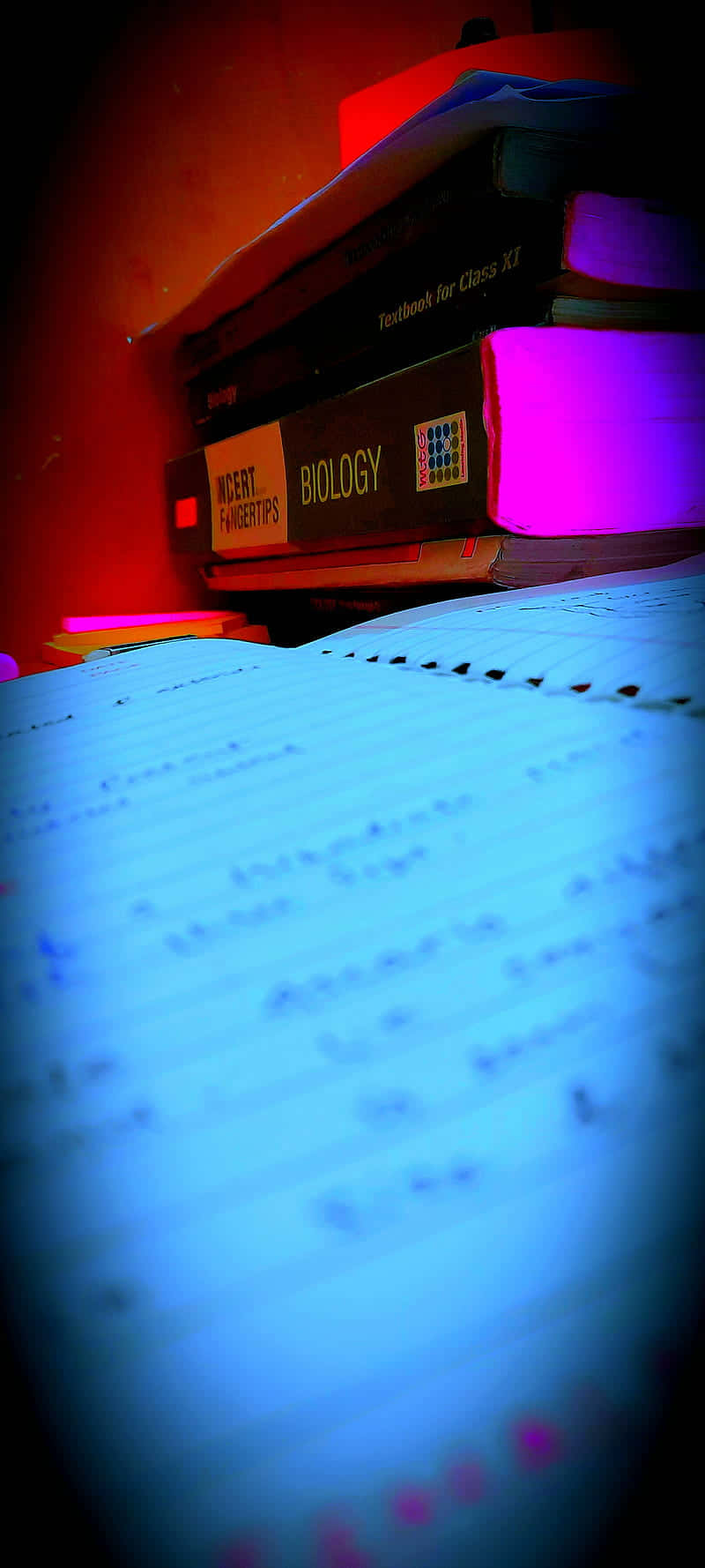 在彩色霓虹燈下堆疊的生物教科書和手寫筆記。