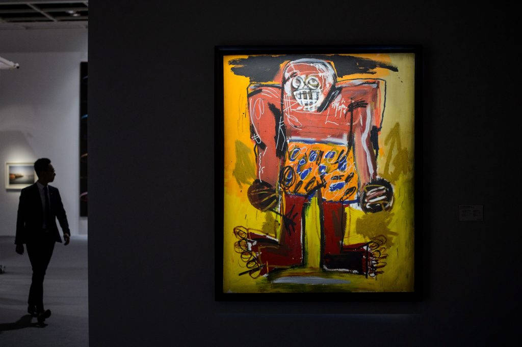 受糖雷·羅賓遜啟發的藝術作品 壁紙 — 一幅大膽的抽象畫，描繪紅色骷髏形象配以黃色背景，懸掛在昏暗的畫廊中，一名男子走過。