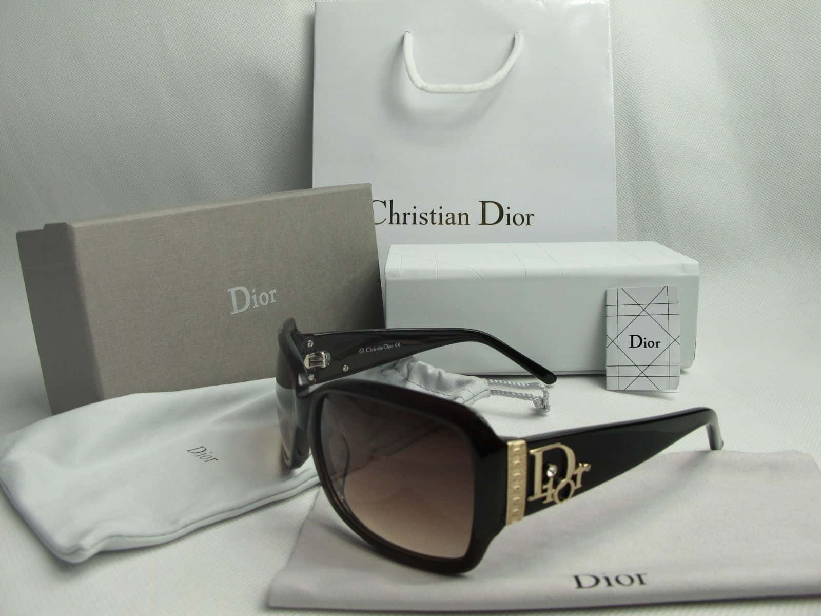 Dior太陽眼鏡連品牌眼鏡盒及配件，置於白色布料上。