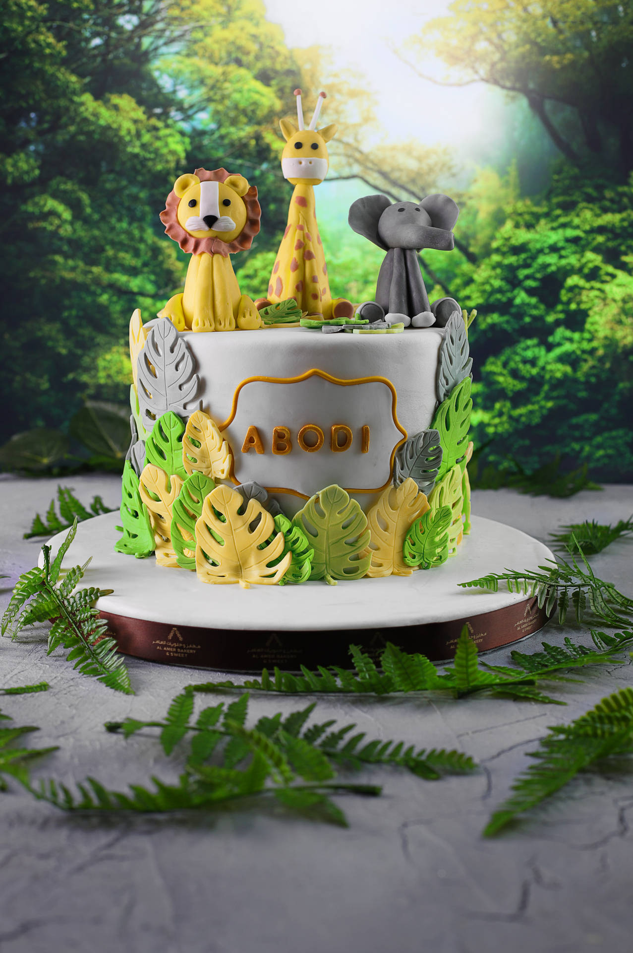 叢林主題生日蛋糕，配有動物裝飾和熱帶樹葉裝飾。